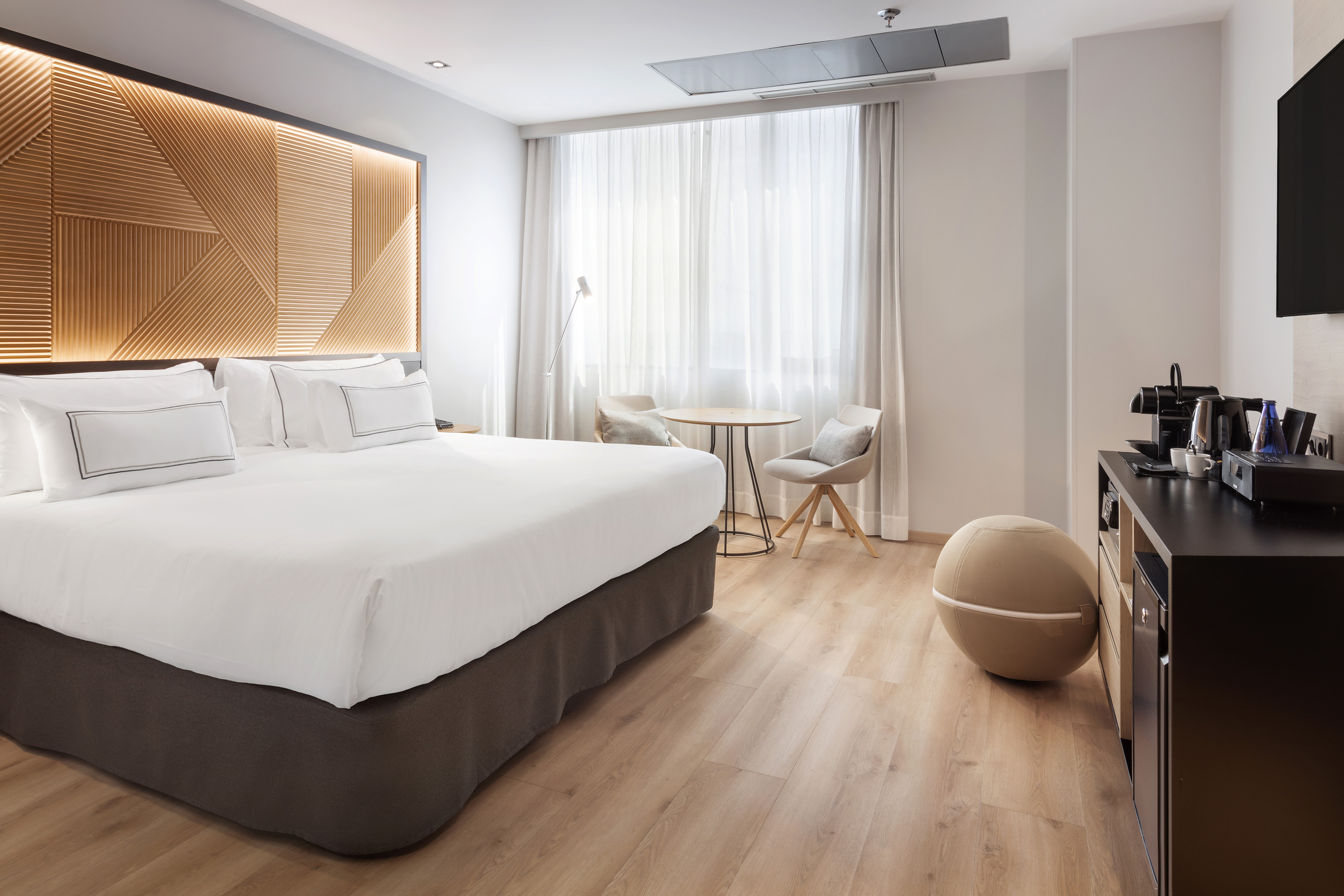 Stylish hotel room with king bed, wooden accent wall, and coffee machine.