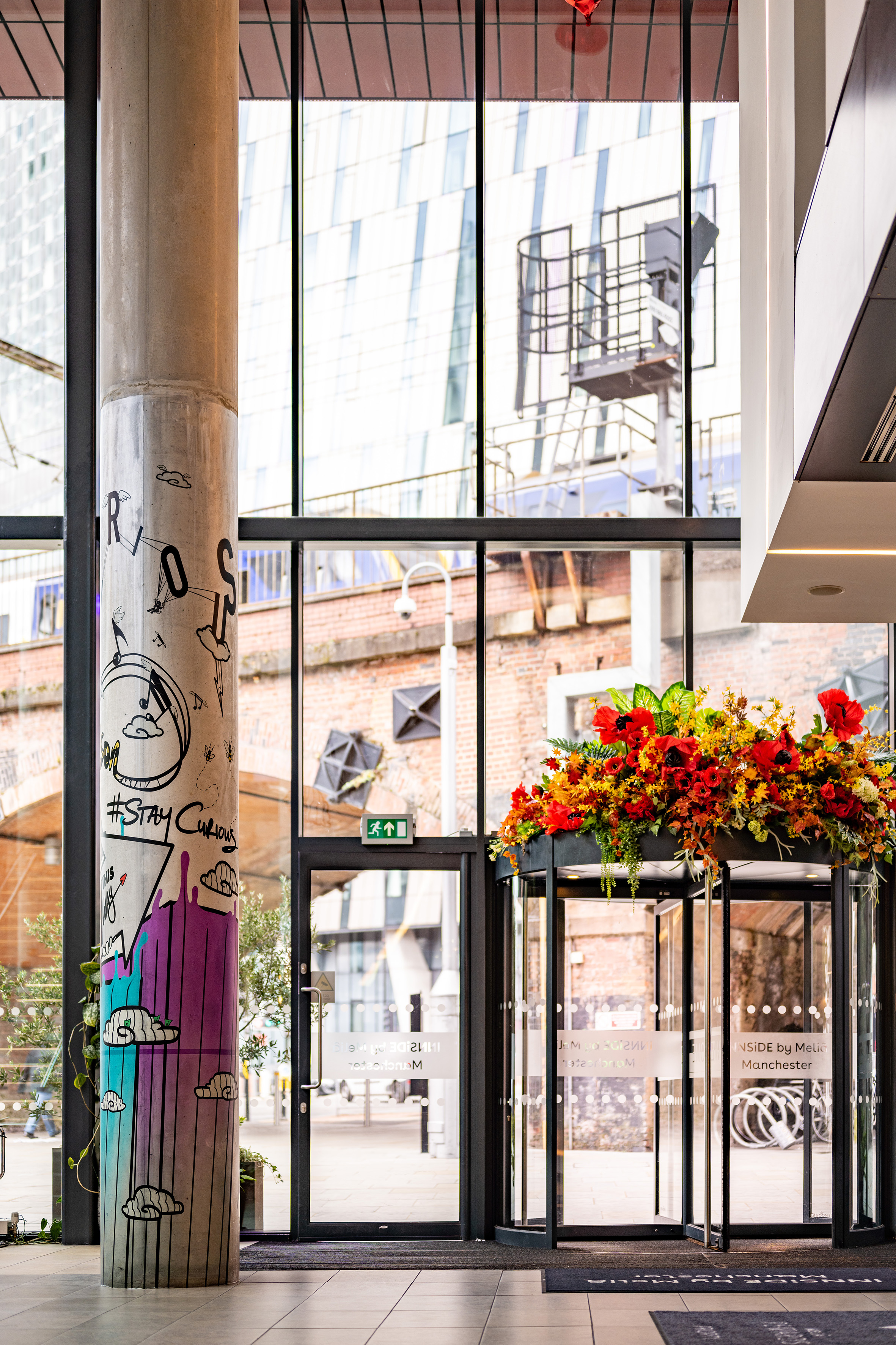 INSIDE by Melia Manchester lobby: graffiti pillar, floral revolving door.