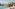 Resort infinity pool overlooking ocean and sandy beach, palm trees, loungers.