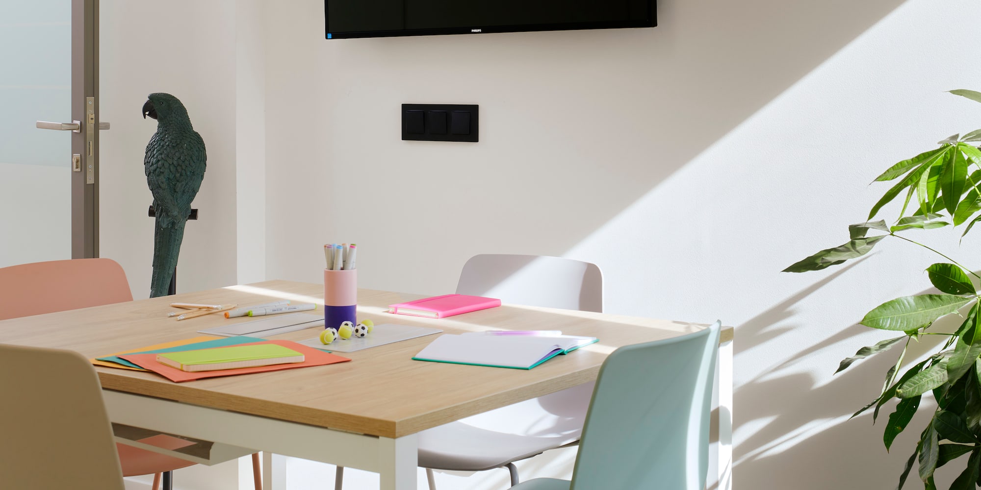 a table with colorful chairs and a tv on the wall