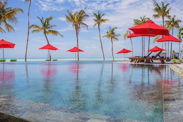 a pool with red umbrellas and palm trees