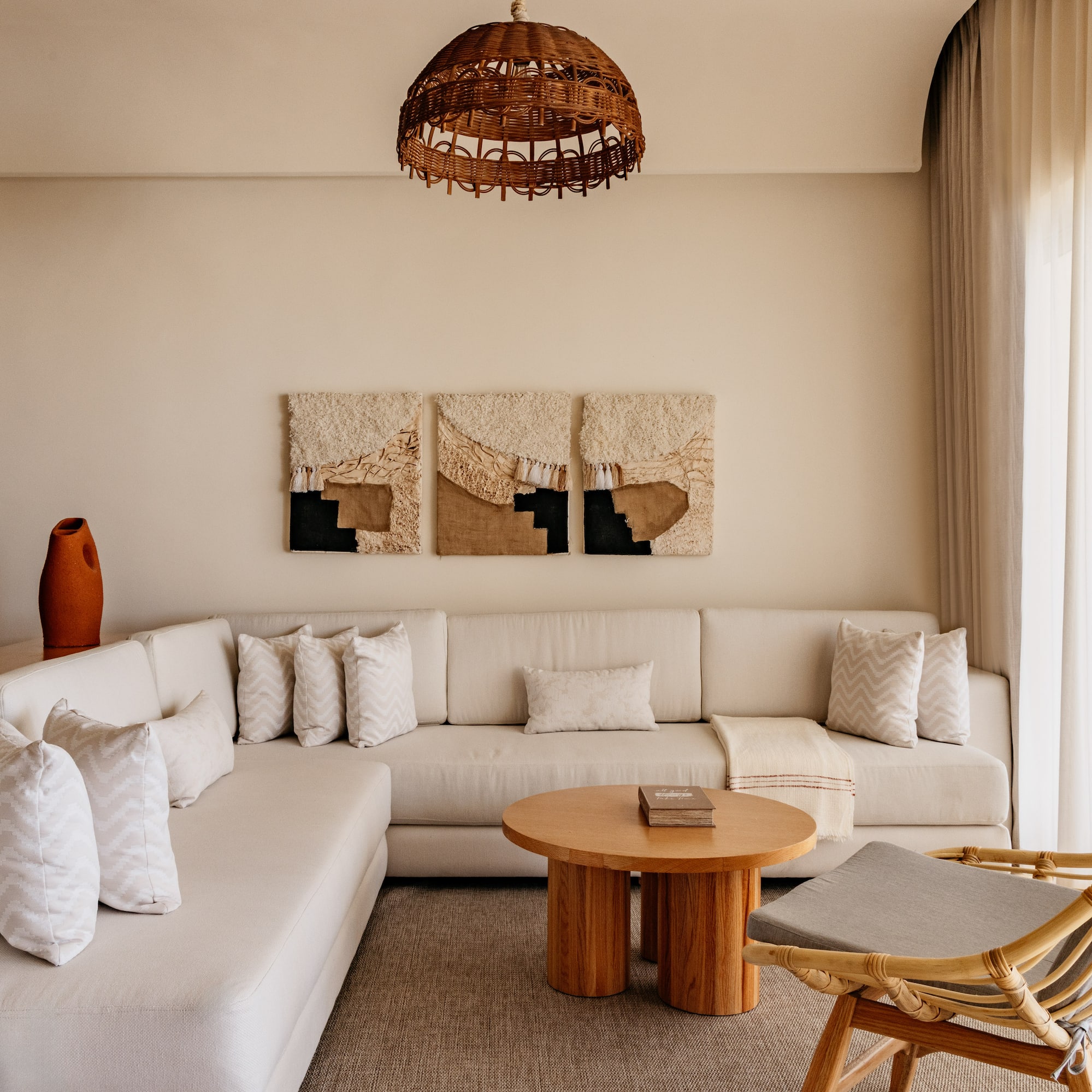 Bohemian living room with neutral L-shaped sofa, rattan chair, and woven decor.