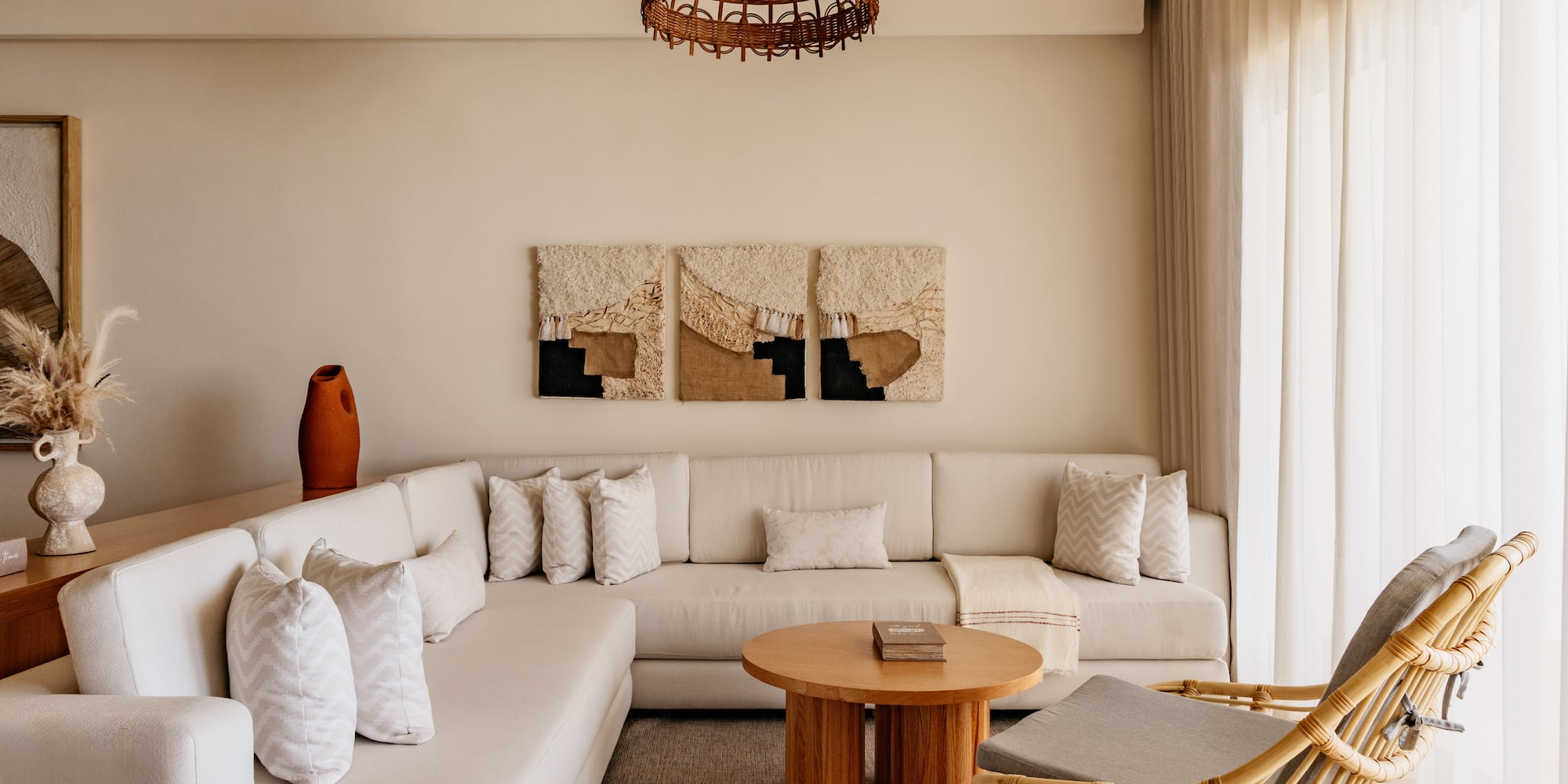 Bohemian living room with neutral L-shaped sofa, rattan chair, and woven decor.