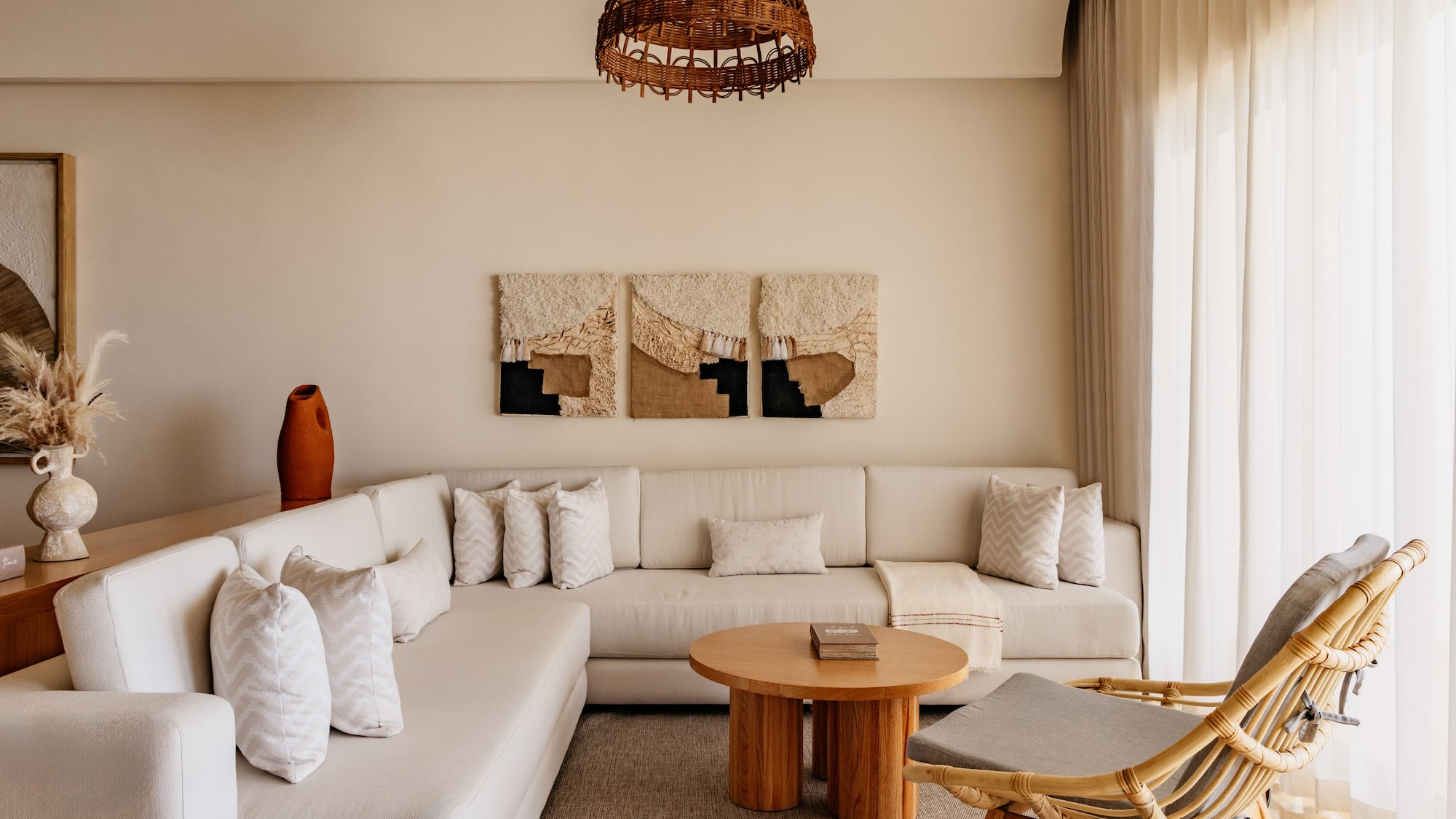 Bohemian living room with neutral L-shaped sofa, rattan chair, and woven decor.