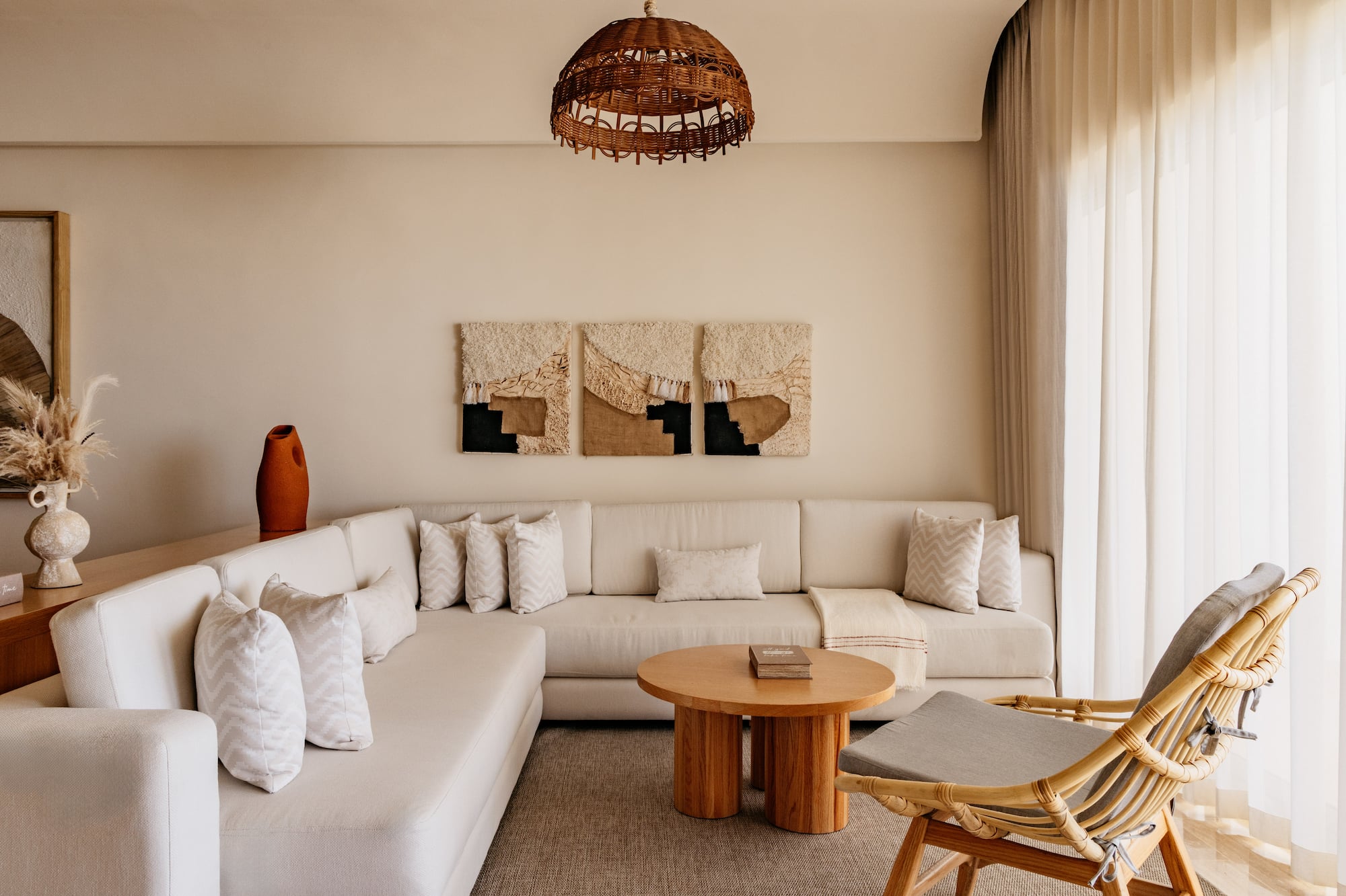 Bohemian living room with neutral L-shaped sofa, rattan chair, and woven decor.