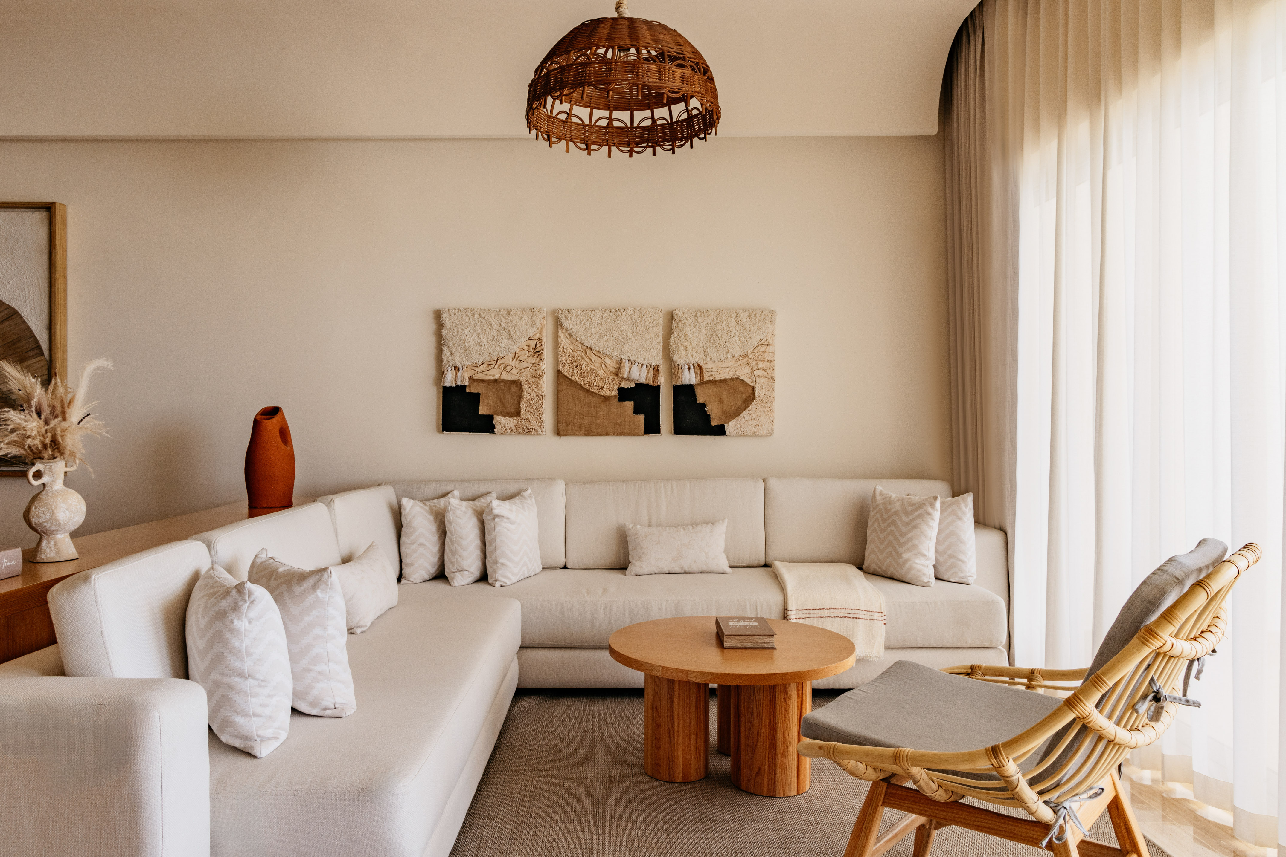 Bohemian living room with neutral L-shaped sofa, rattan chair, and woven decor.
