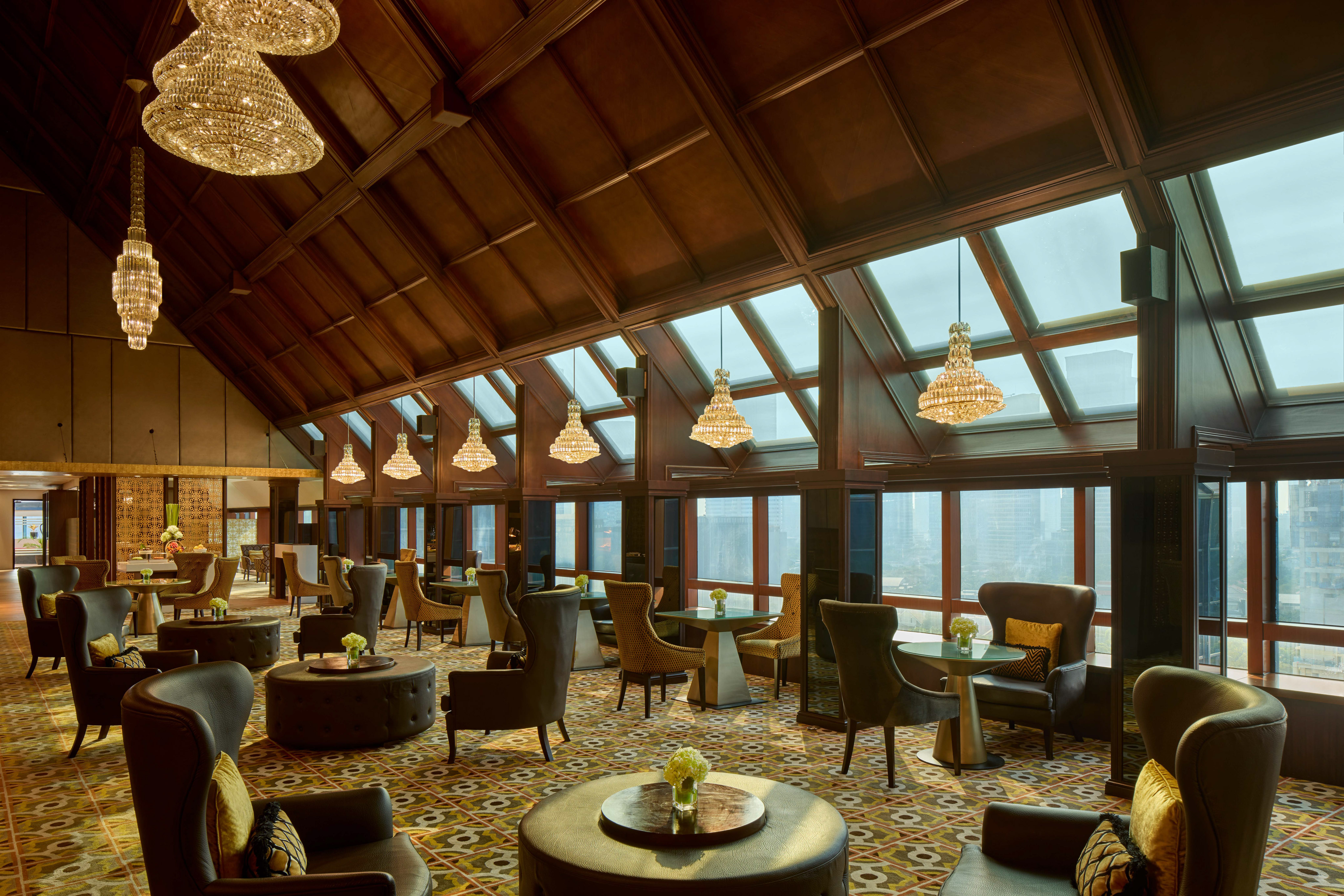Luxury lounge with crystal chandeliers, wood ceiling, and panoramic city view.