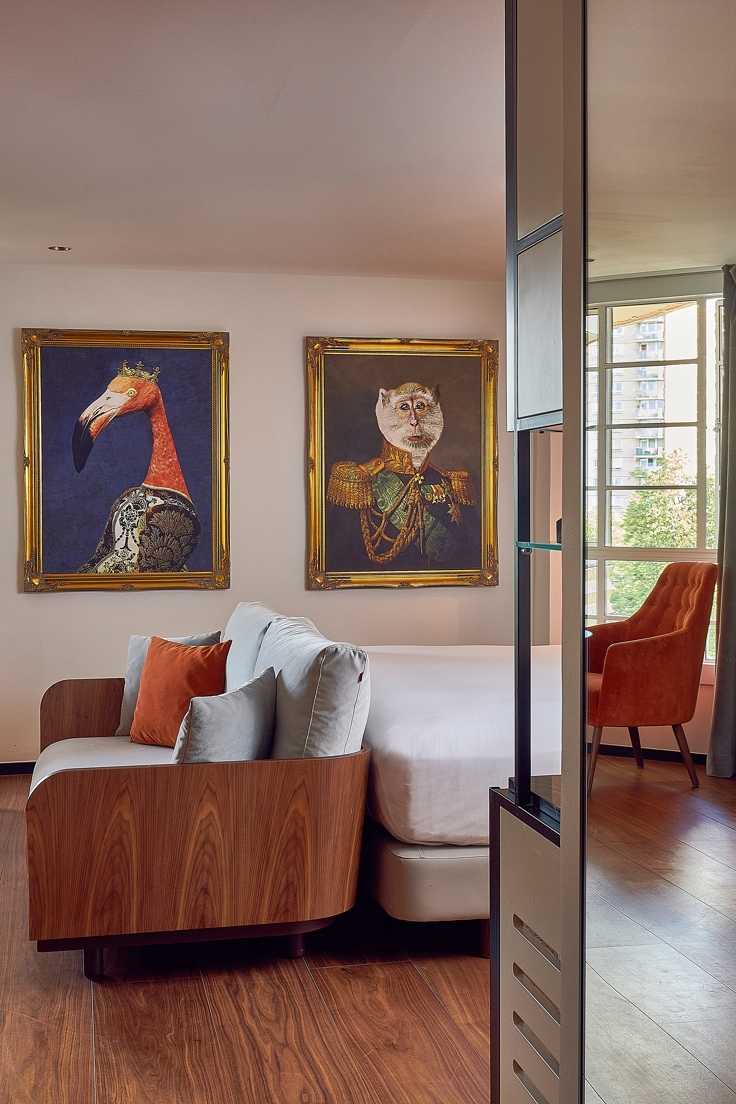 Stylish room with unique flamingo and monkey portraits, wood sofa, and bed.