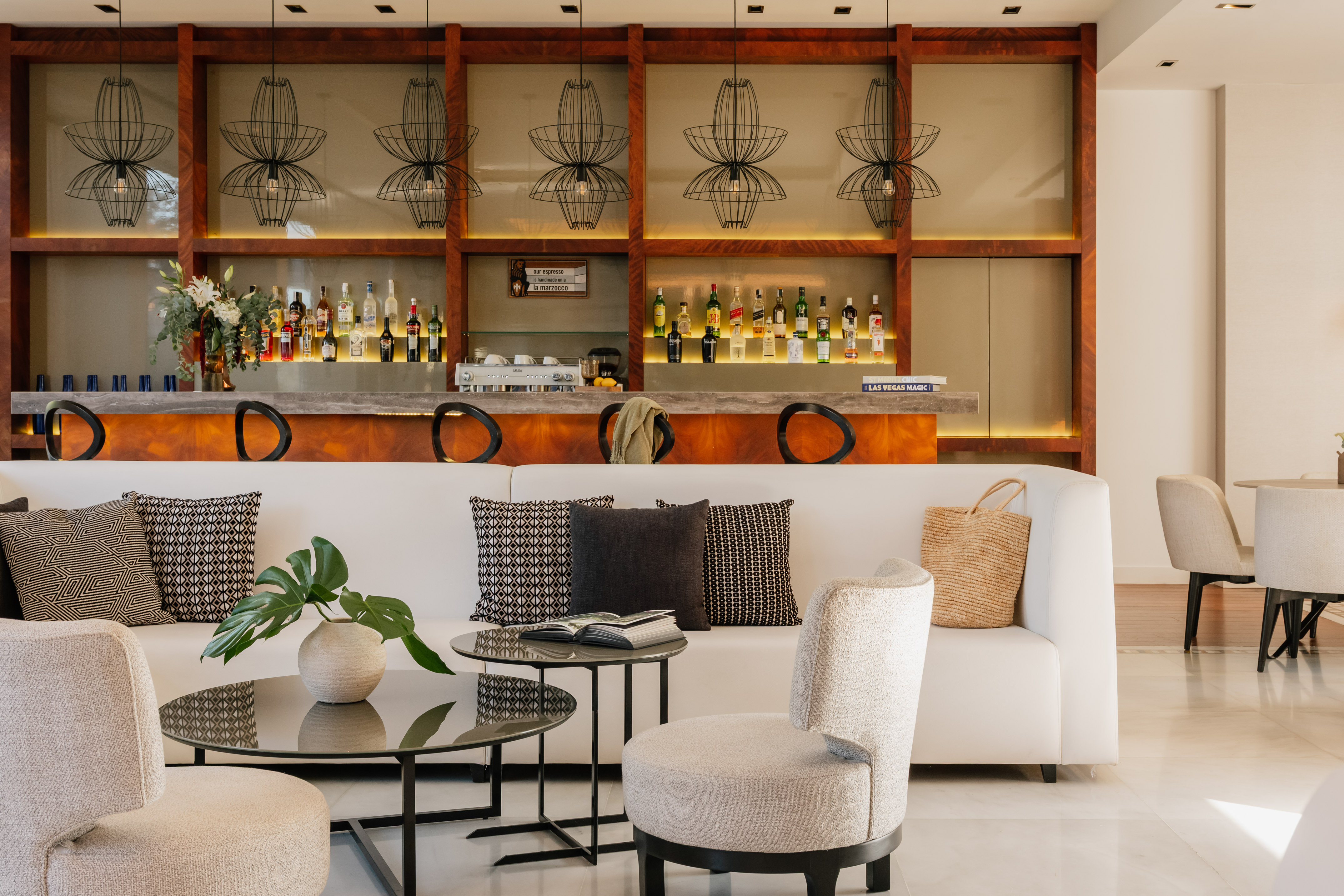 Modern hotel bar lounge with white sofa, stylish counter, and unique pendant lights.