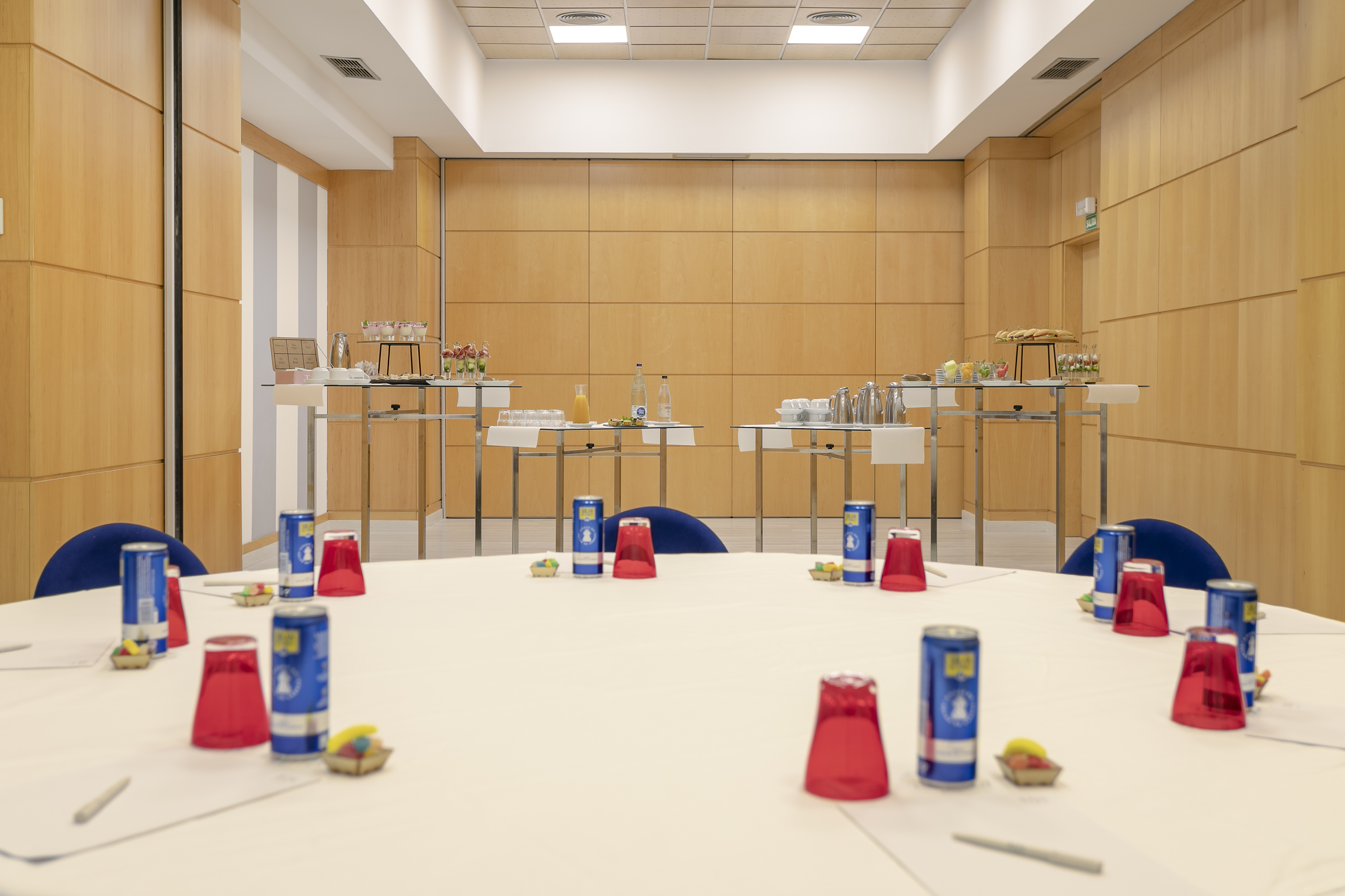 Conference room with refreshment buffet and round tables for business meetings.