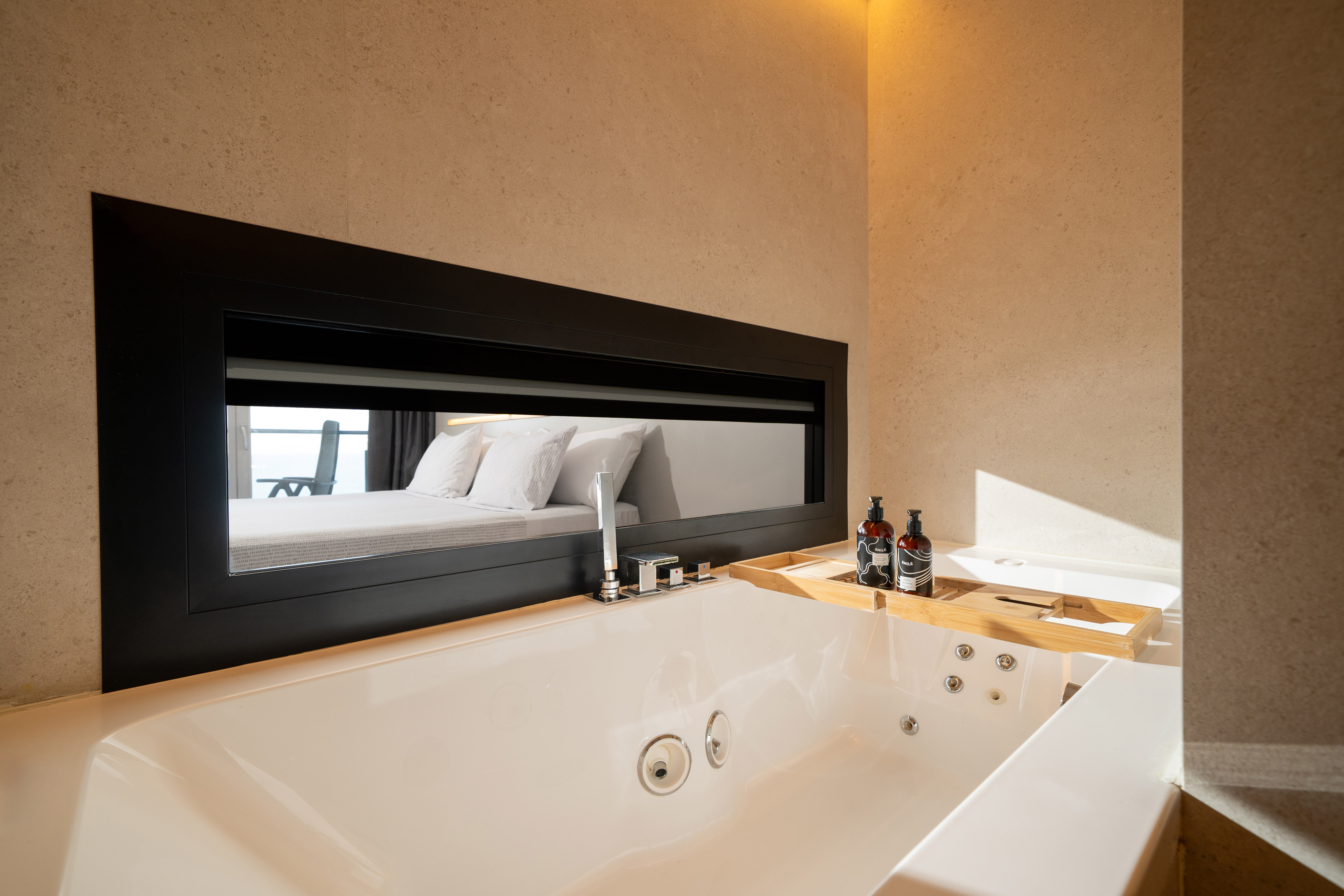 Luxurious jacuzzi tub in hotel bathroom with bedroom view window.