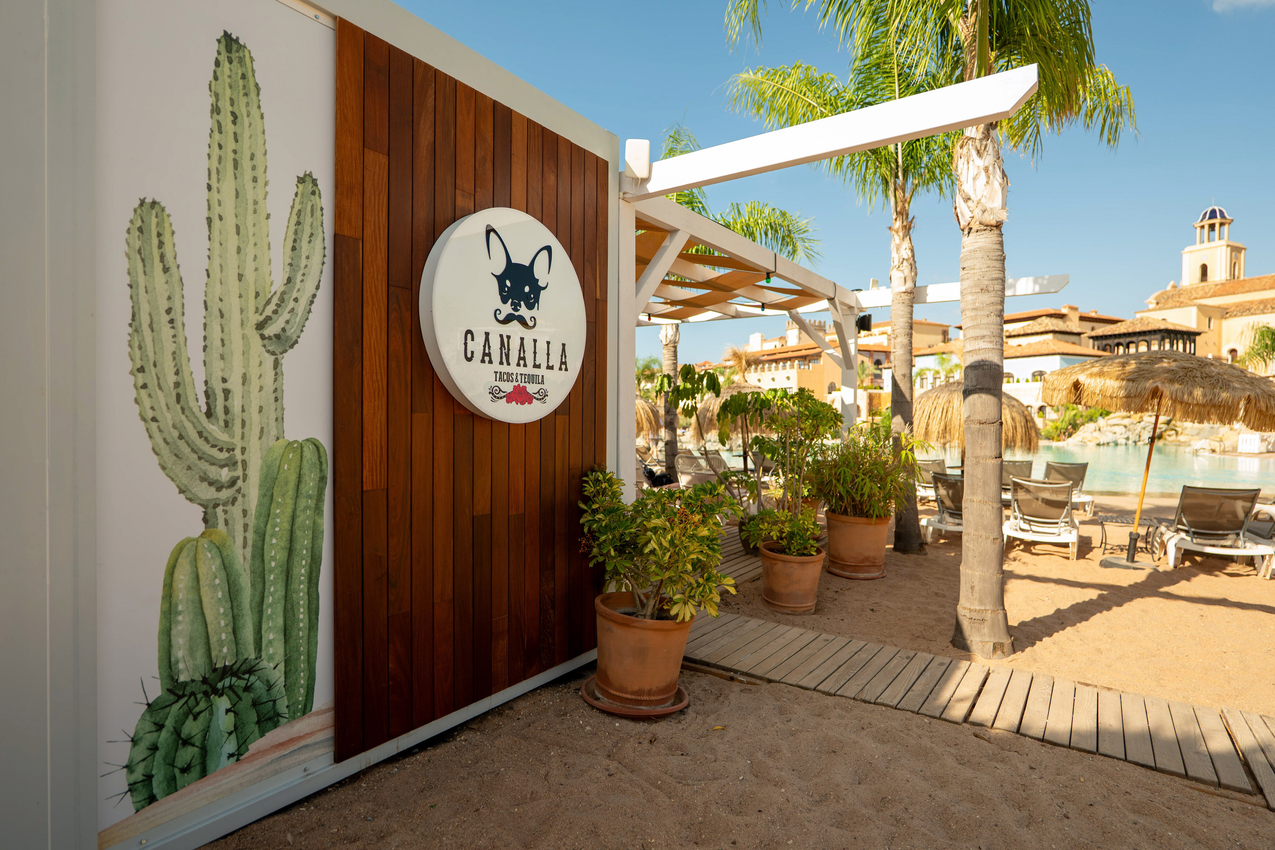 Canalla Tacos & Tequila sign with cactus mural at a tropical pool resort.