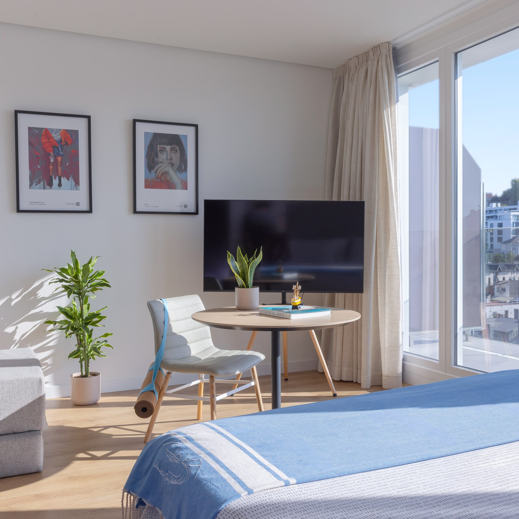 Apartamento luminoso con cama, sofá, ventanal y arte, vistas urbanas.