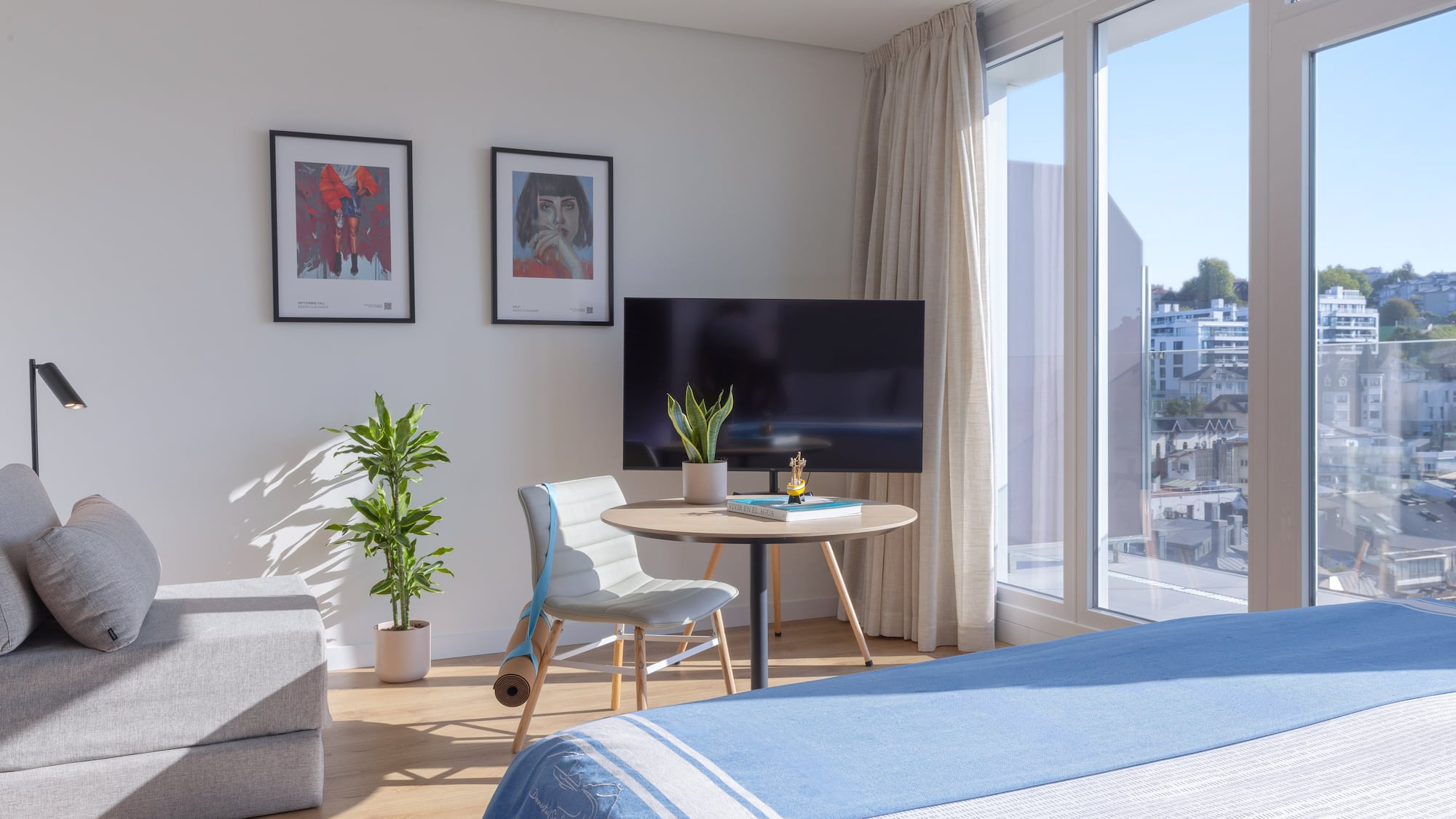 Apartamento luminoso con cama, sofá, ventanal y arte, vistas urbanas.
