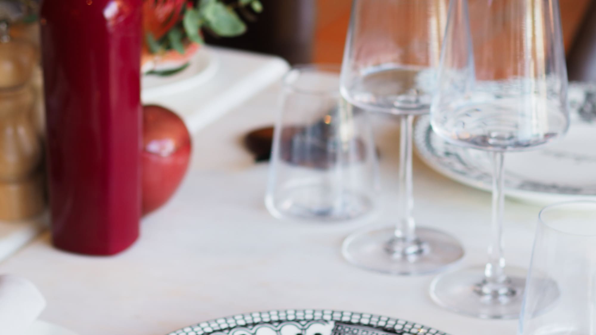 Restaurant table setting with Burladero plate, wine glasses, red bottle.