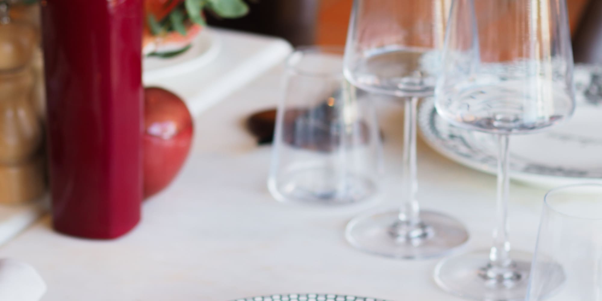 Restaurant table setting with Burladero plate, wine glasses, red bottle.