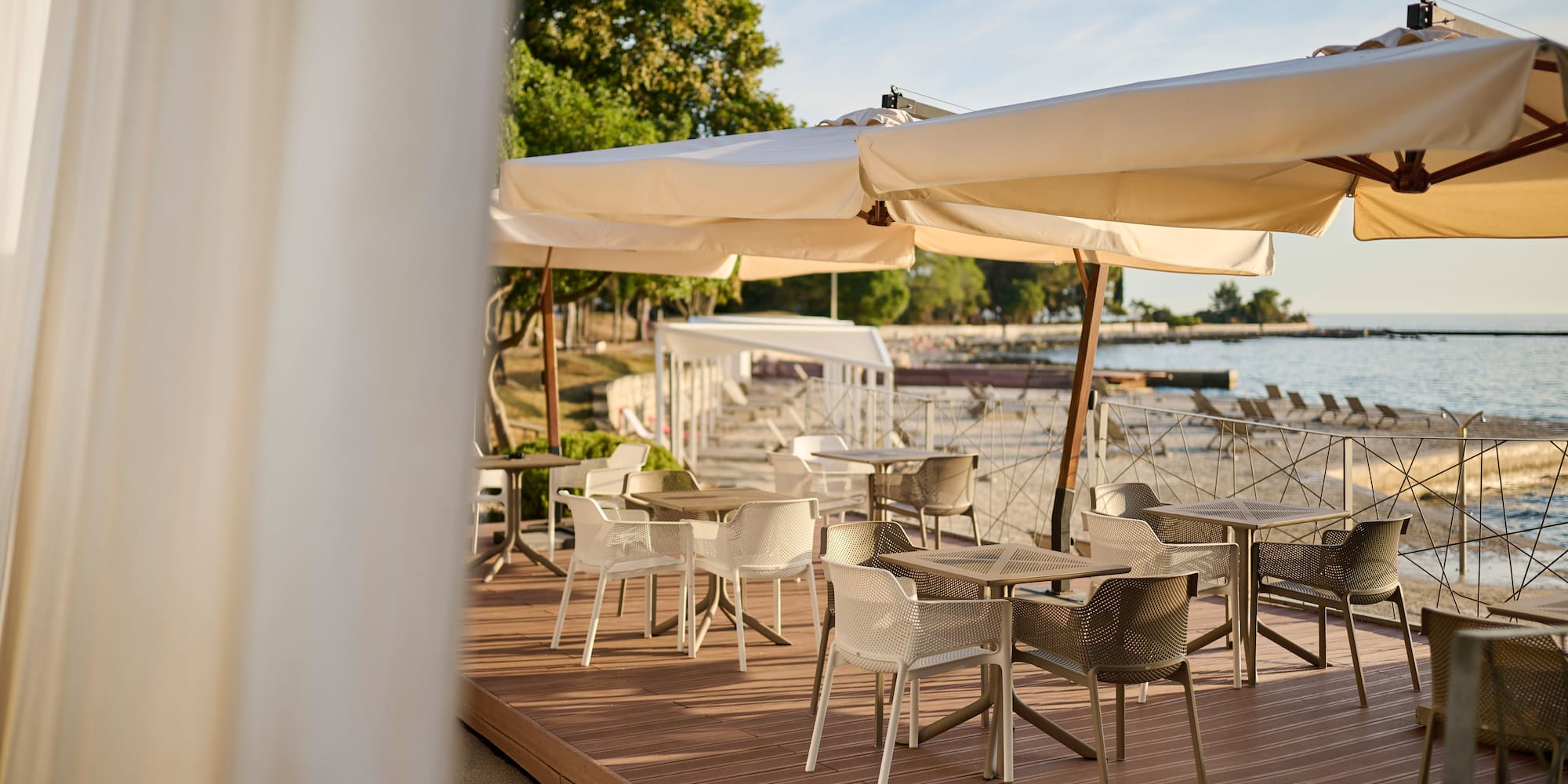 a table and chairs on a deck with a large white umbrella