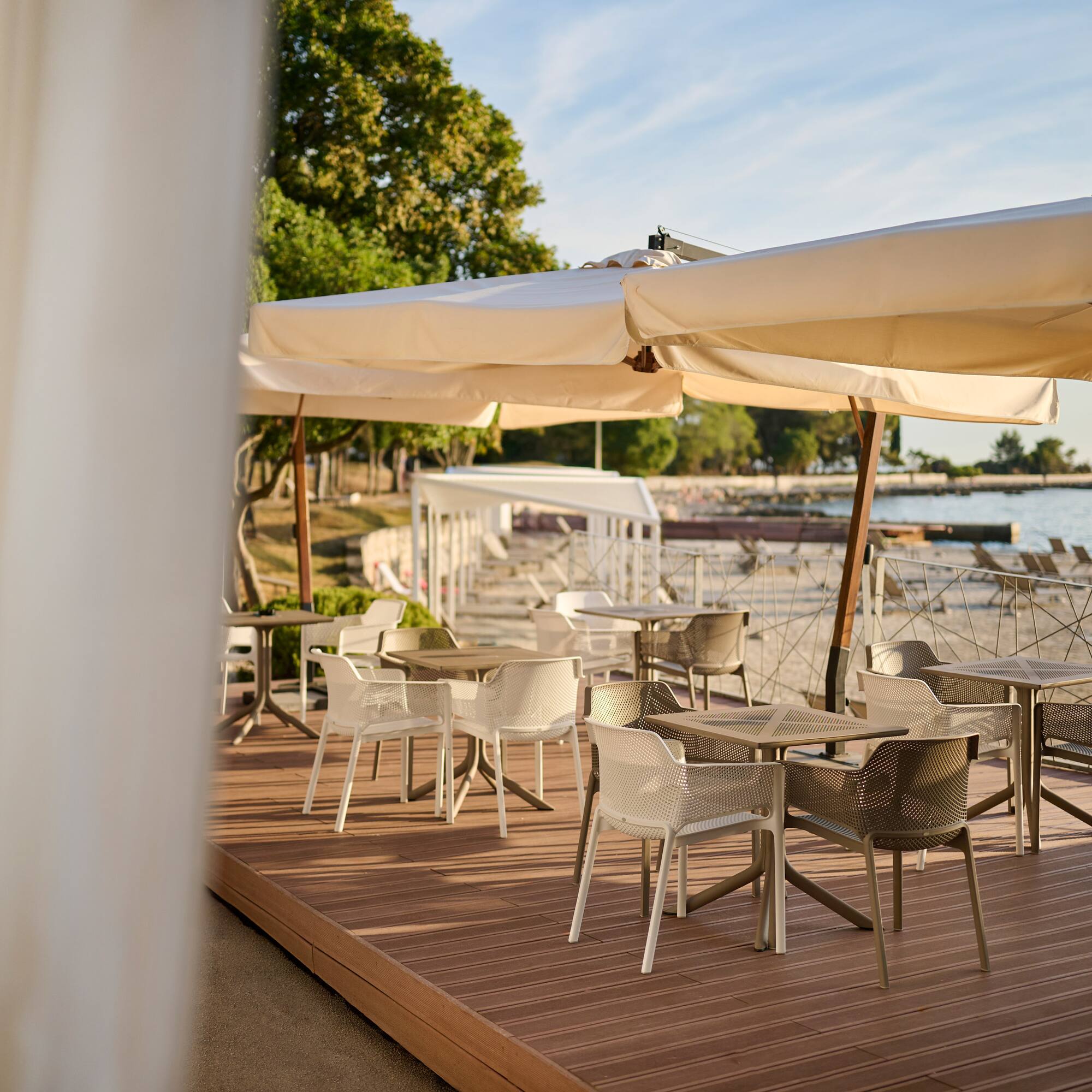 a table and chairs on a deck with a large white umbrella