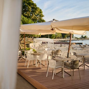 a table and chairs on a deck with a large white umbrella