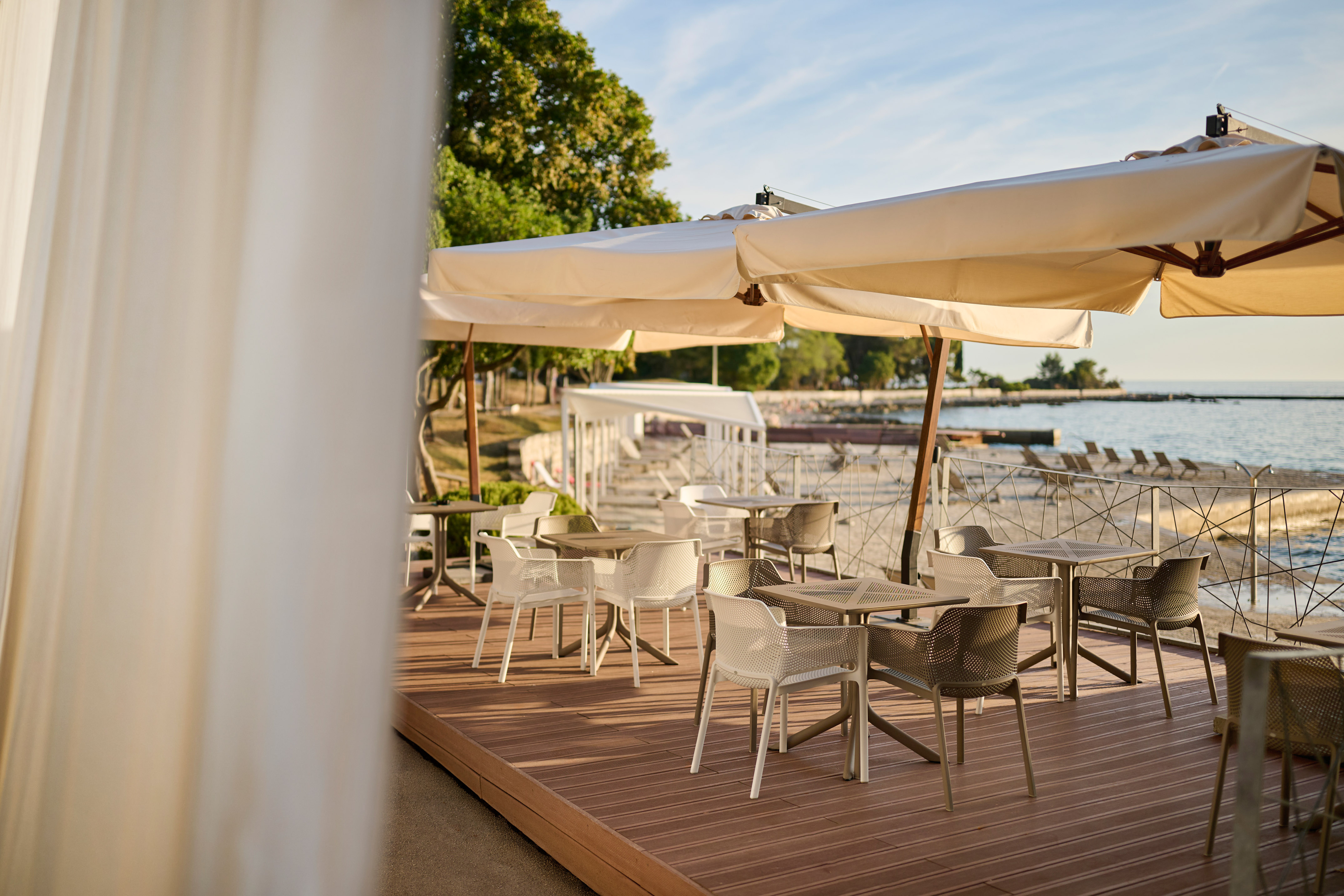 a table and chairs on a deck with a large white umbrella