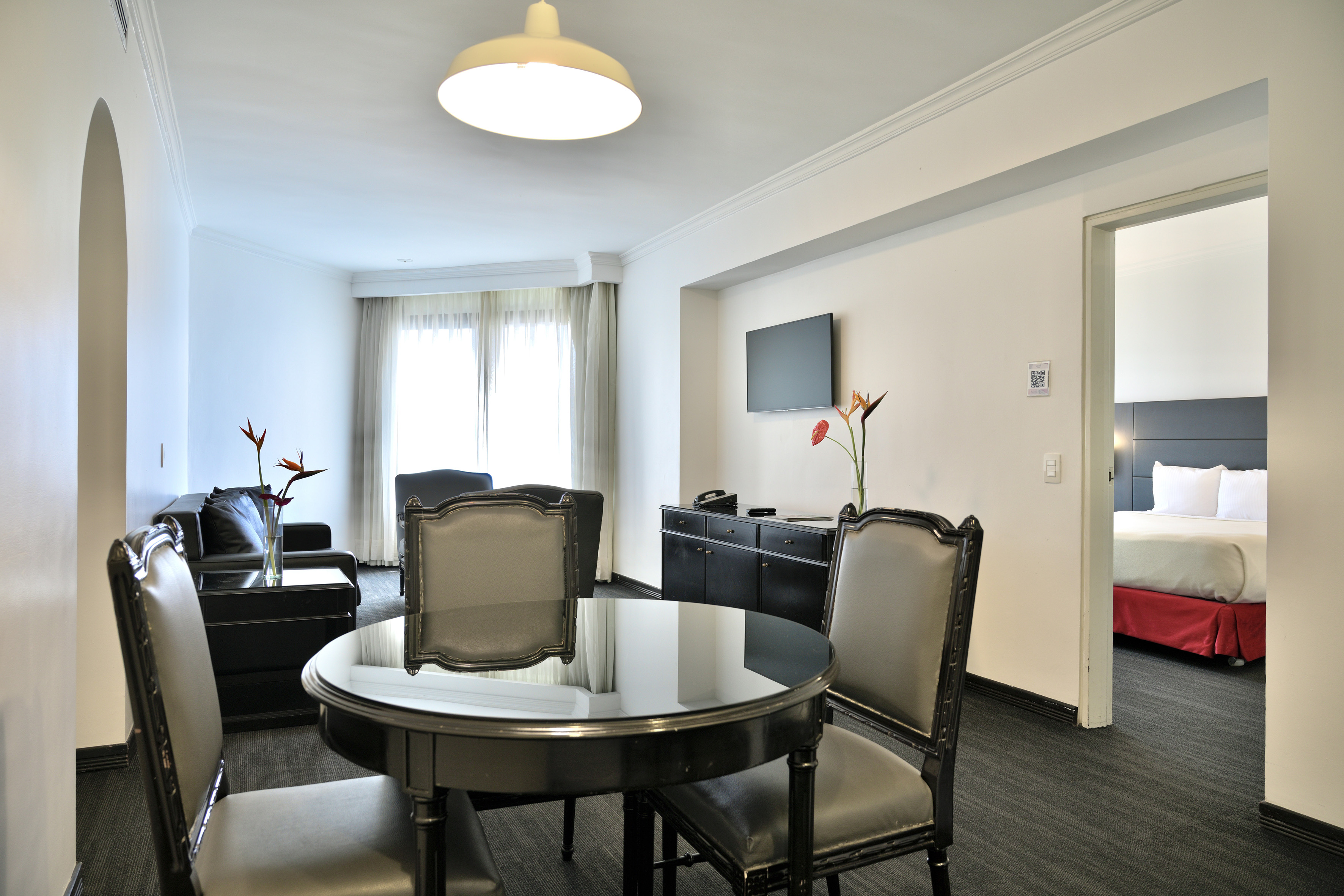 Elegant hotel suite with dining area, living room, and connected bedroom.