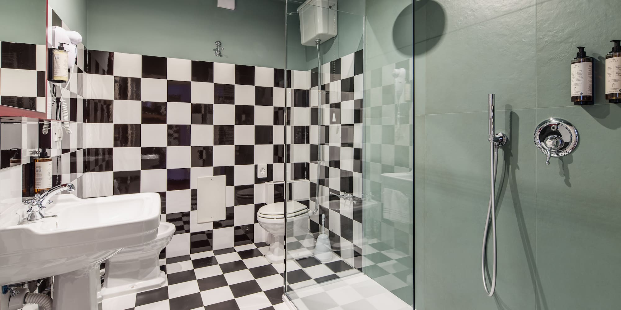 Bathroom with black and white checkerboard tiles, green walls, shower, toilet, and sink.