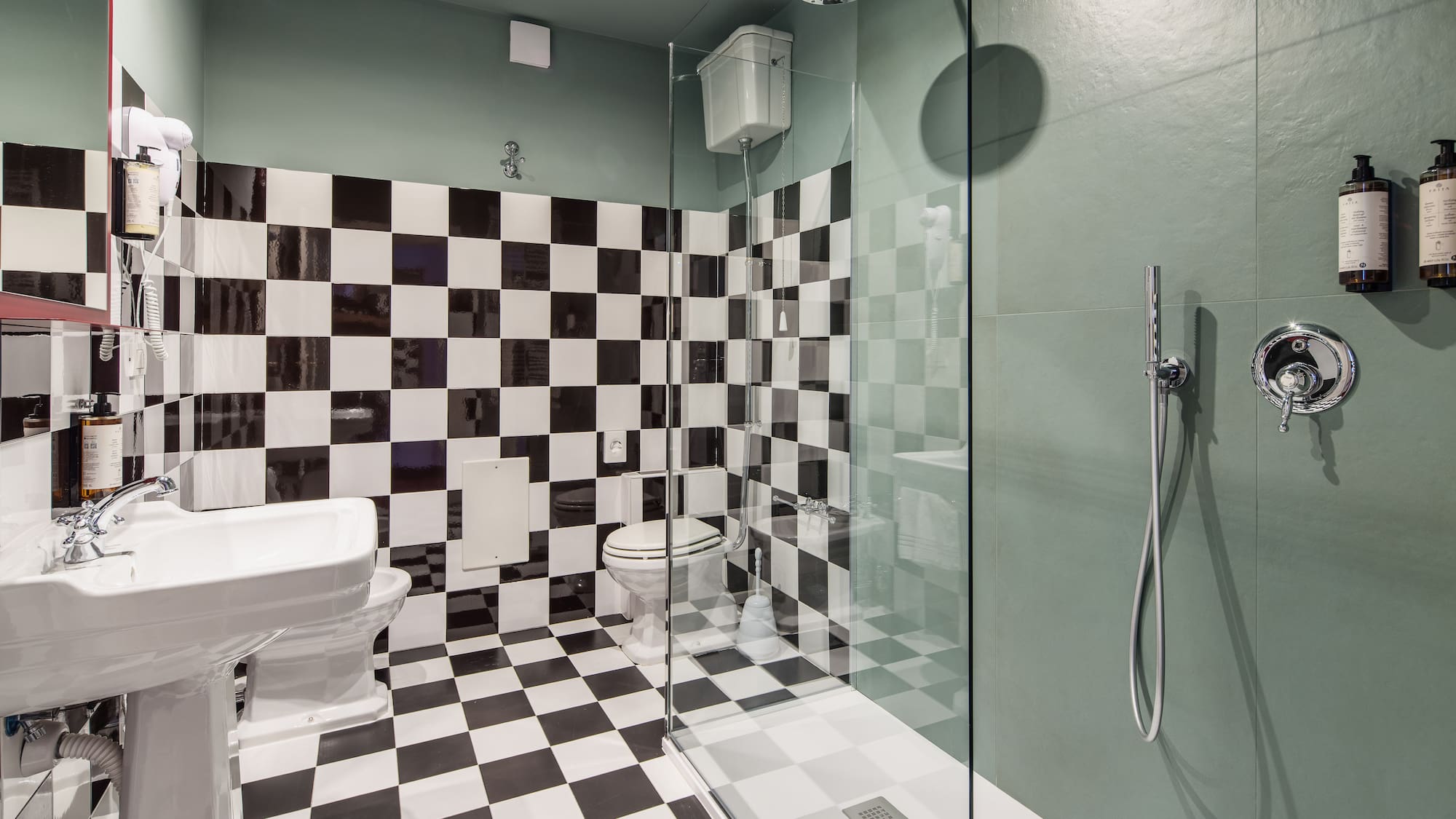 Bathroom with black and white checkerboard tiles, green walls, shower, toilet, and sink.