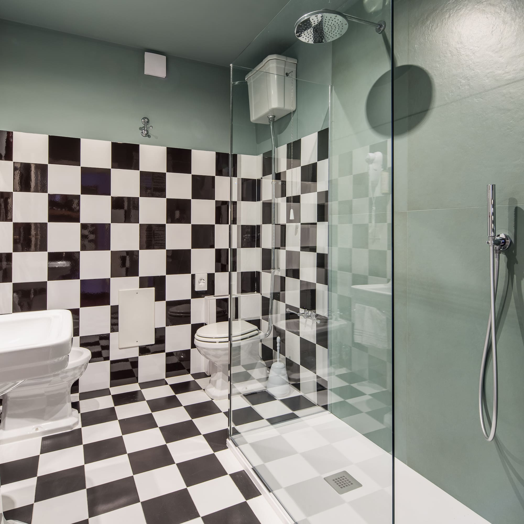 Bathroom with black and white checkerboard tiles, green walls, shower, toilet, and sink.