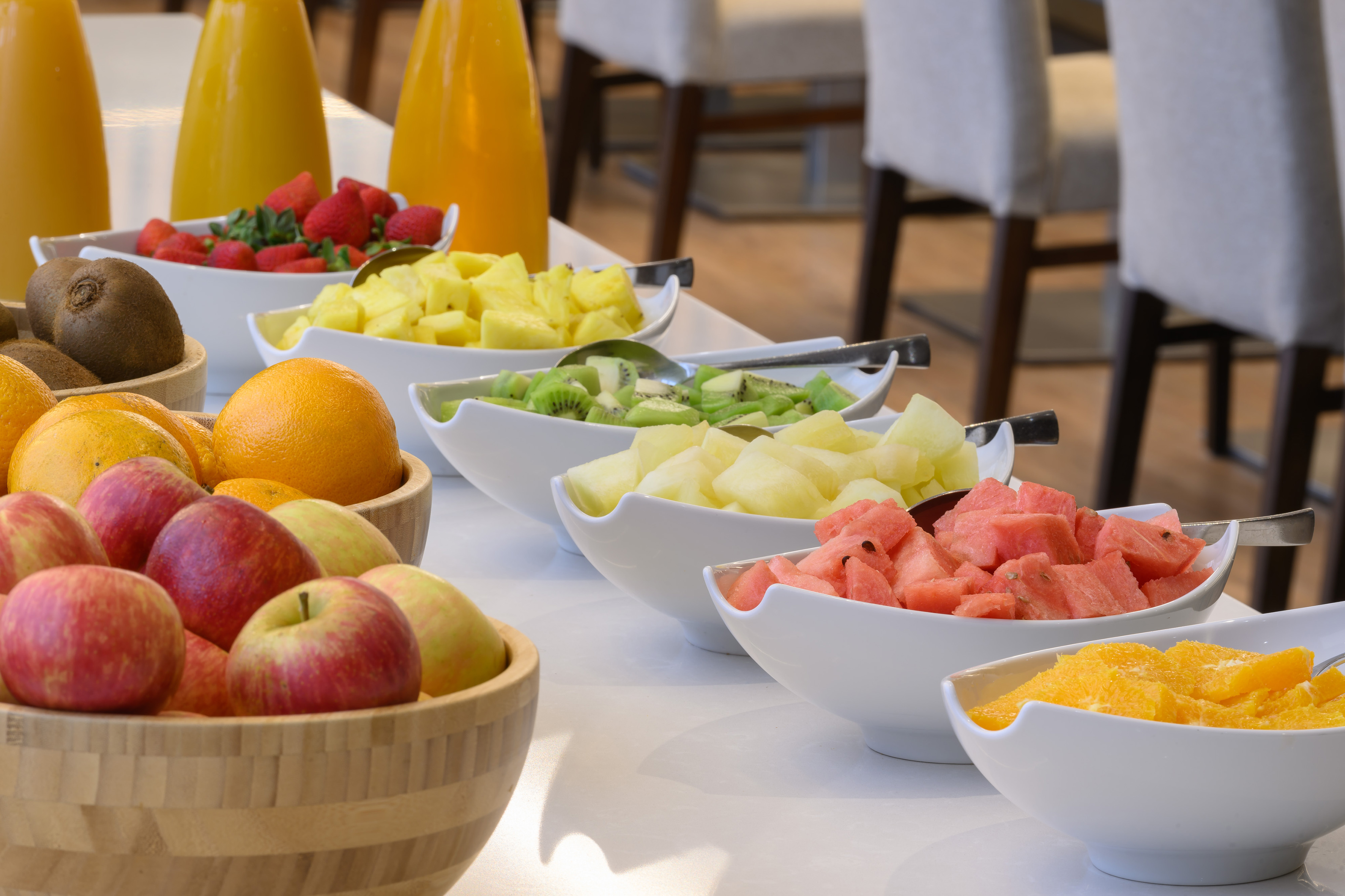 Fresh fruit breakfast buffet with assorted fruit bowls and orange juice.