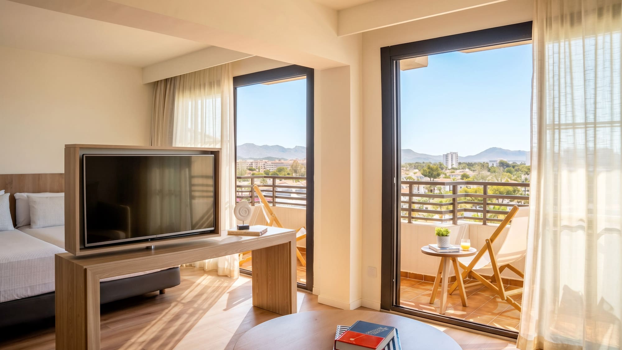 Bright hotel suite with balcony, TV, and scenic mountain views.