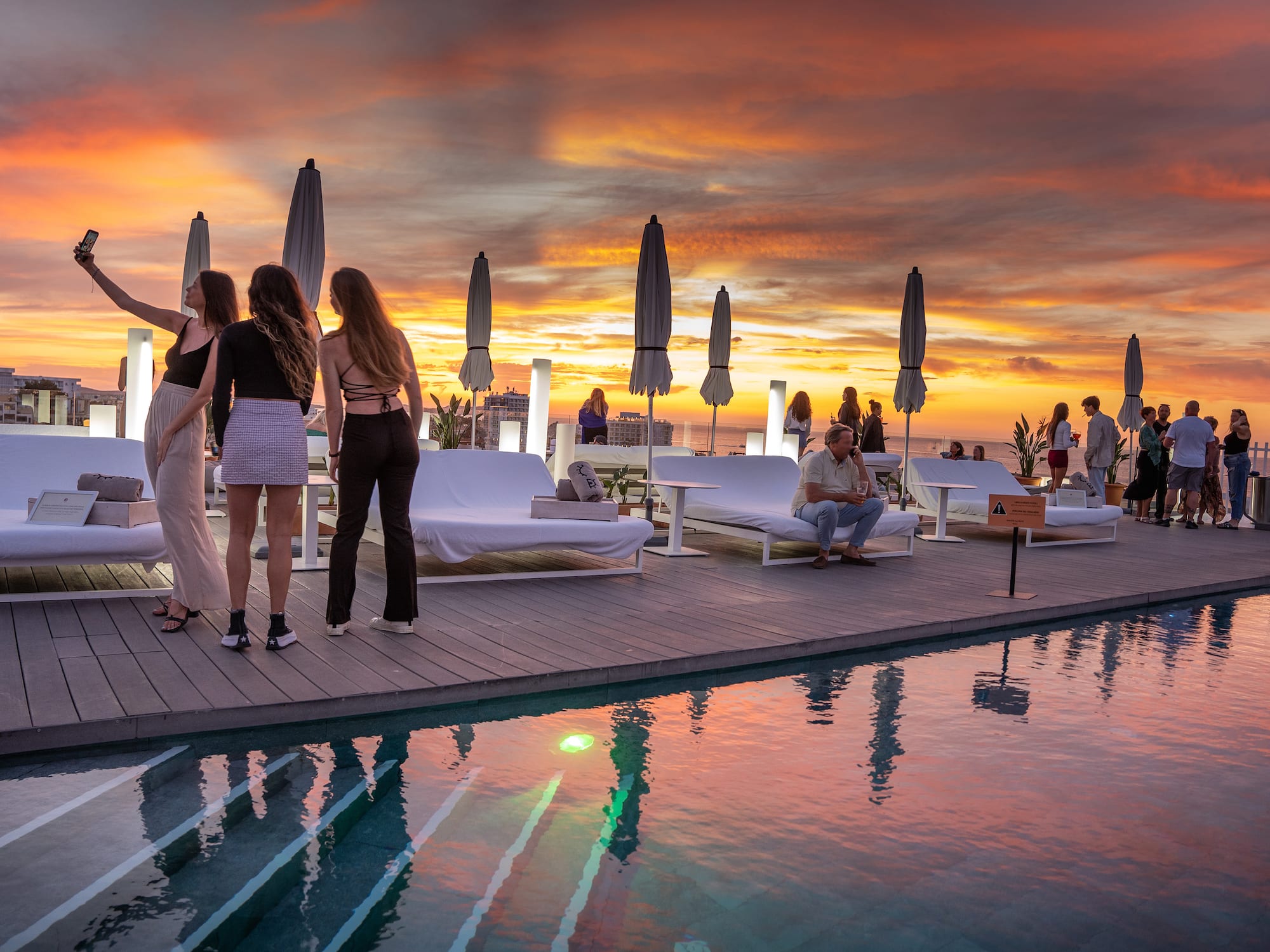 a group of people standing on a deck near a pool