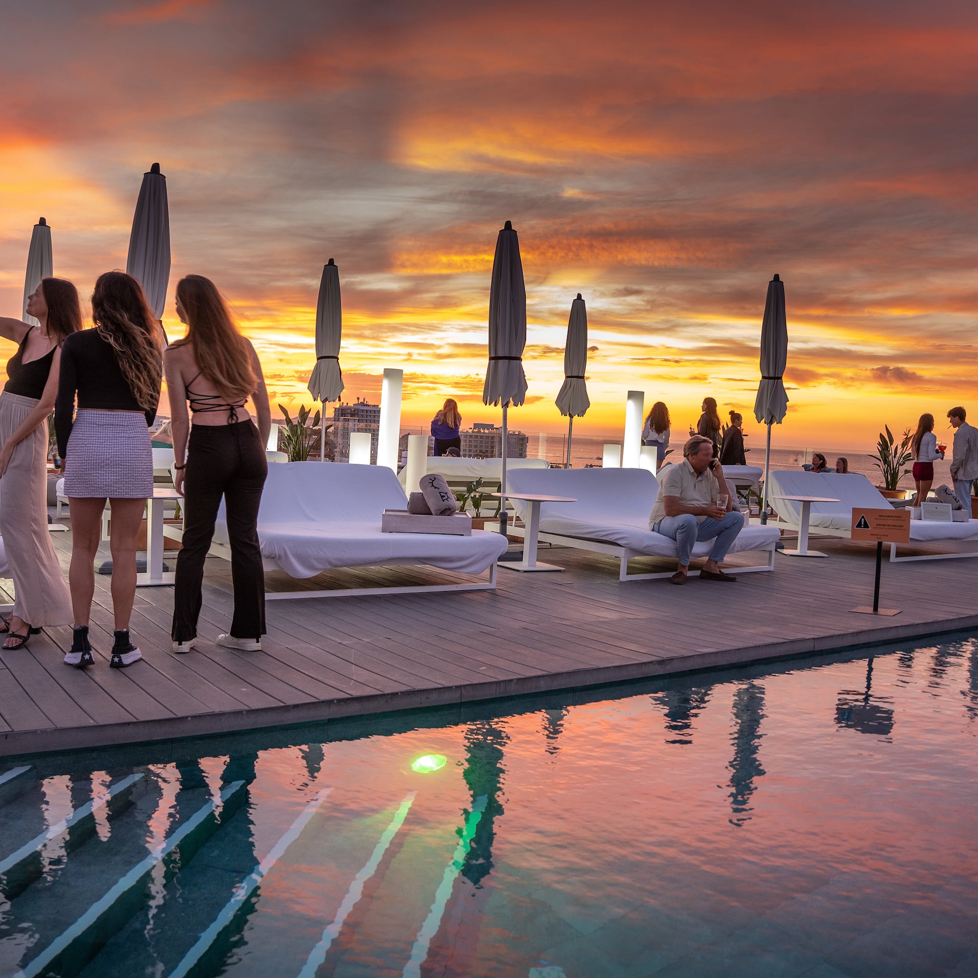 a group of people standing on a deck near a pool