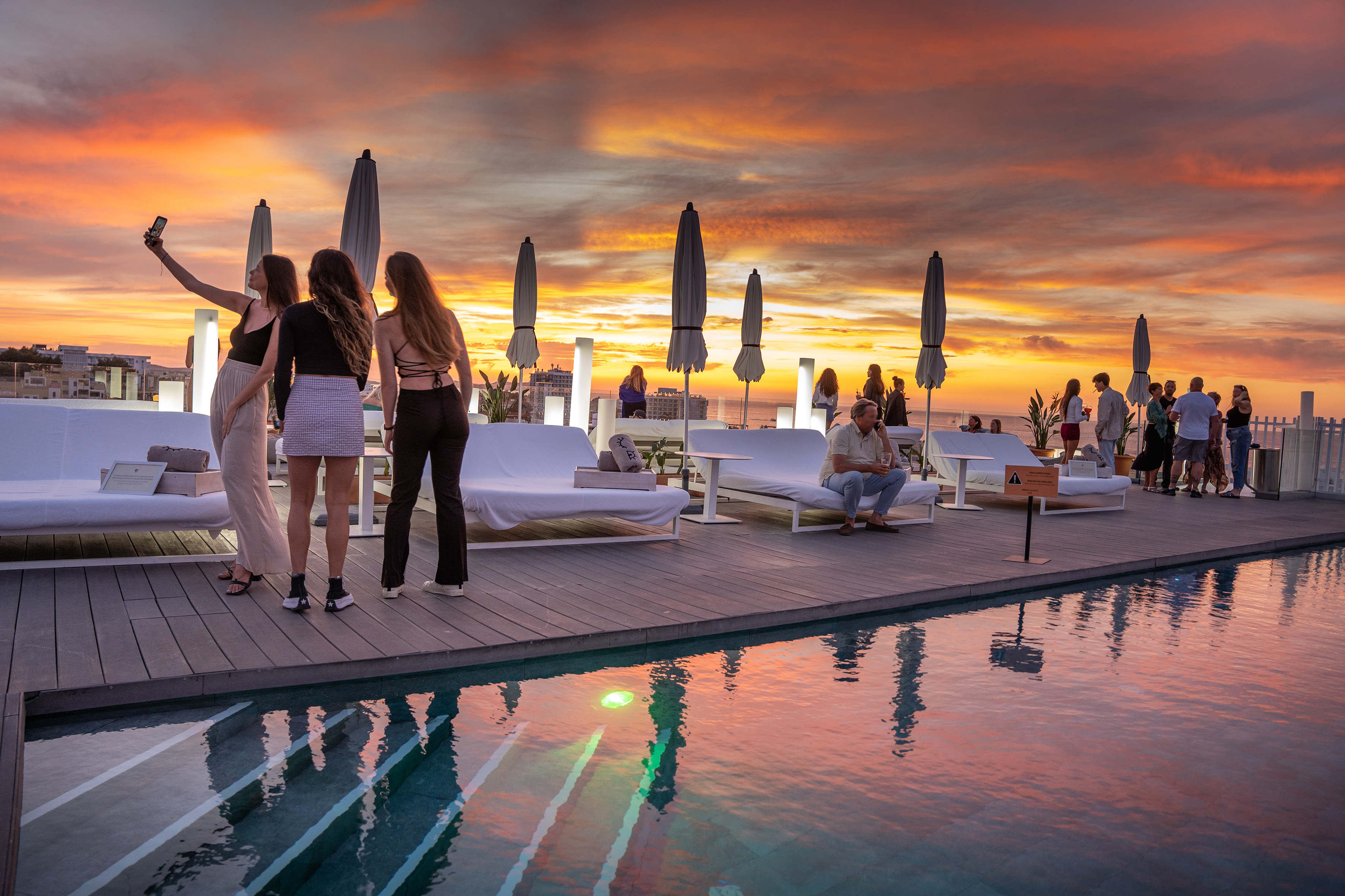 a group of people standing on a deck near a pool