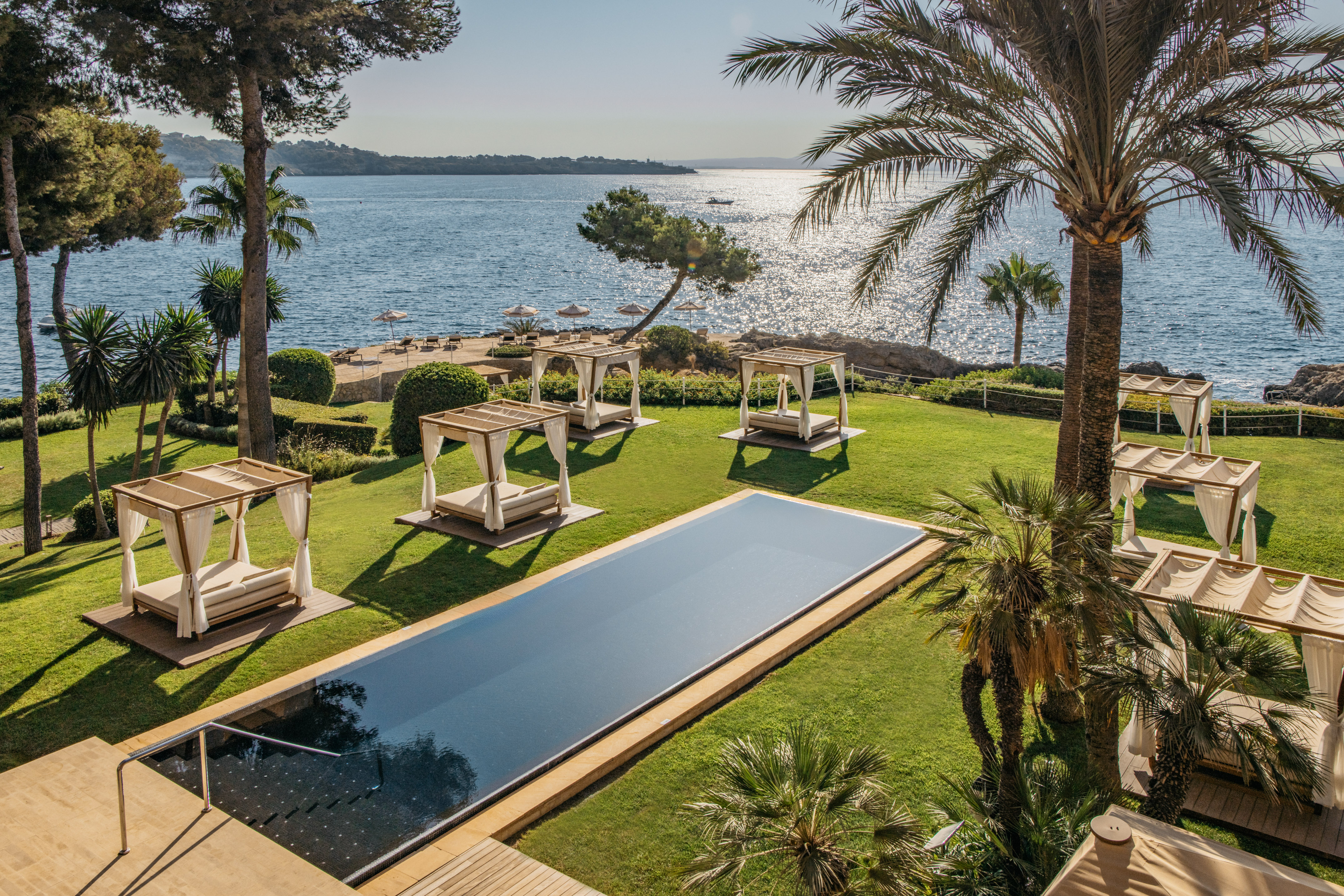 Luxury resort with infinity pool, cabanas, palm trees, and sparkling ocean view.