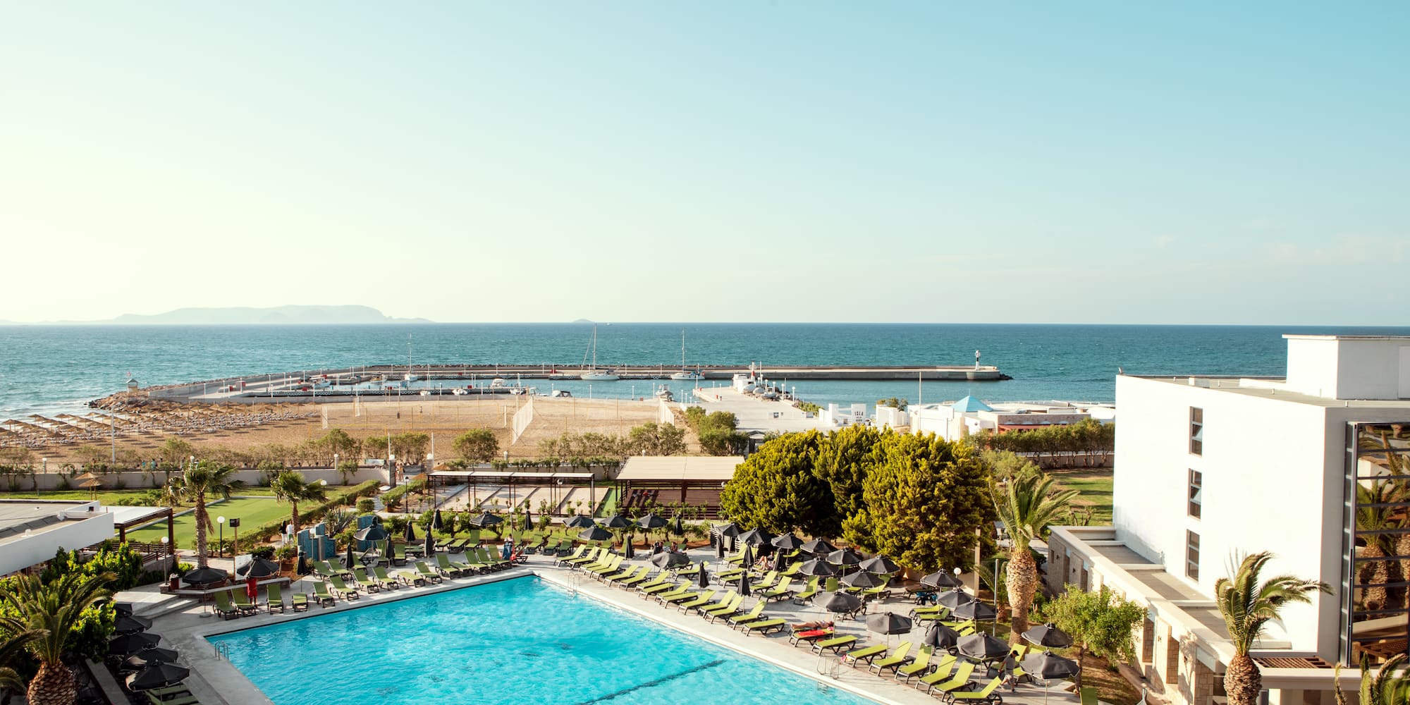 a swimming pool with chairs and a beach in the background