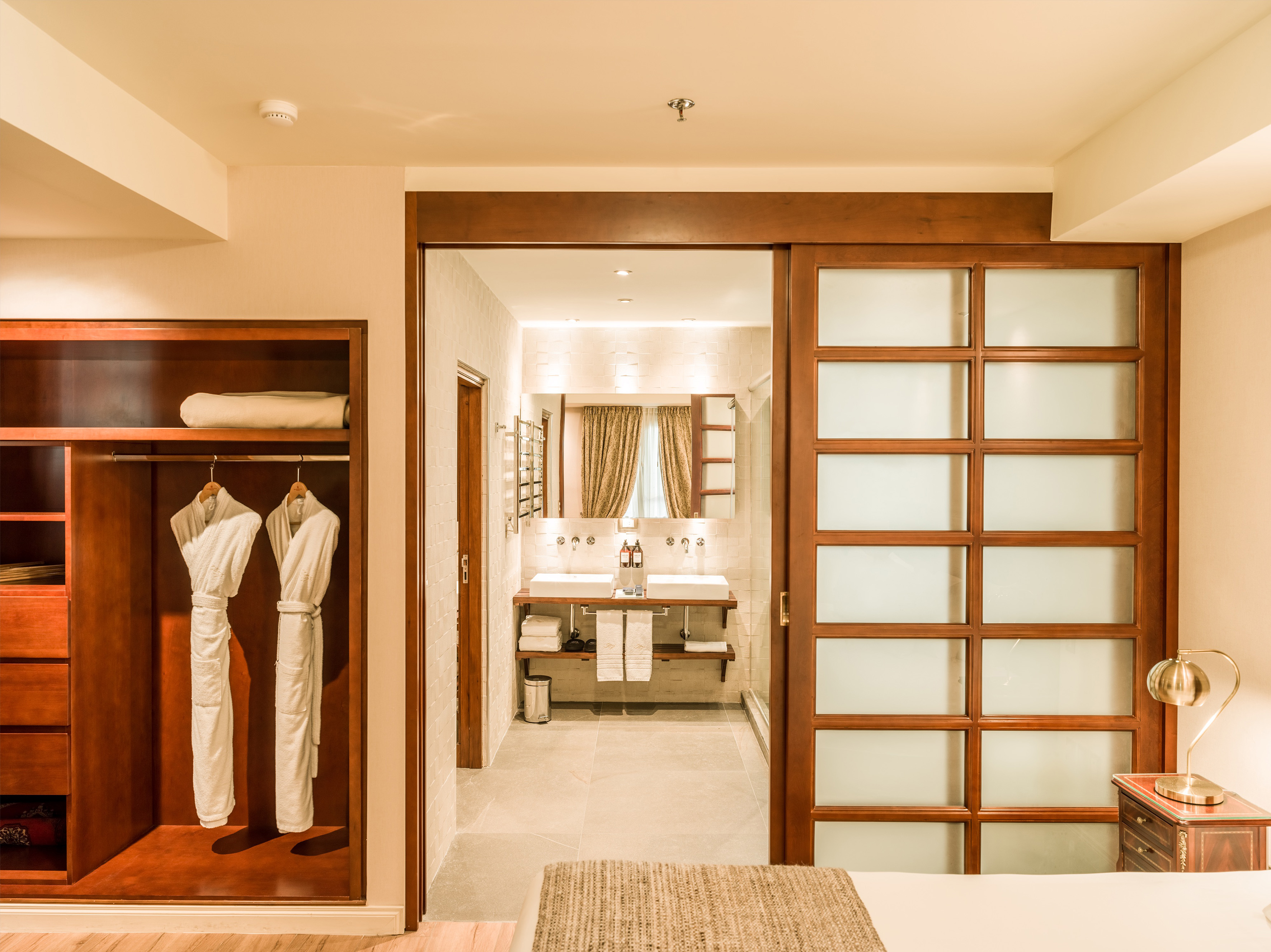 Hotel bedroom with open wardrobe, bathrobes, and modern en-suite bathroom.