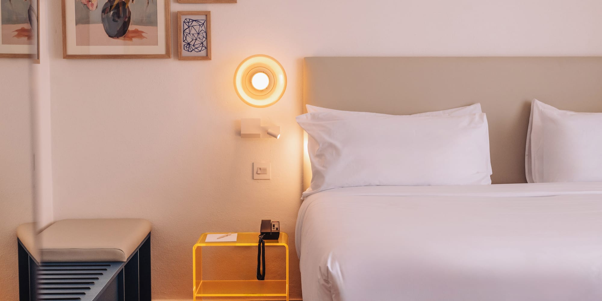a bed with a yellow end table and a lamp