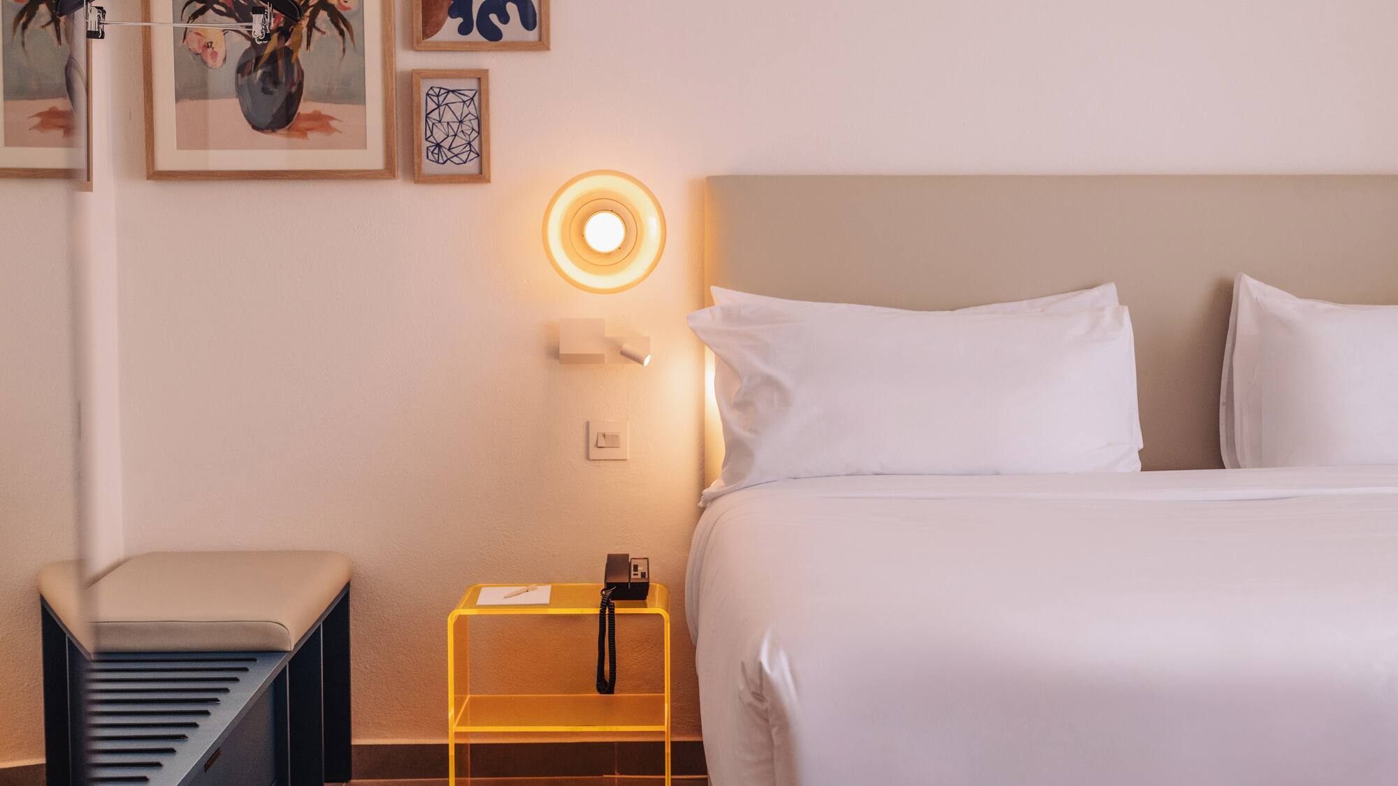a bed with a yellow end table and a lamp