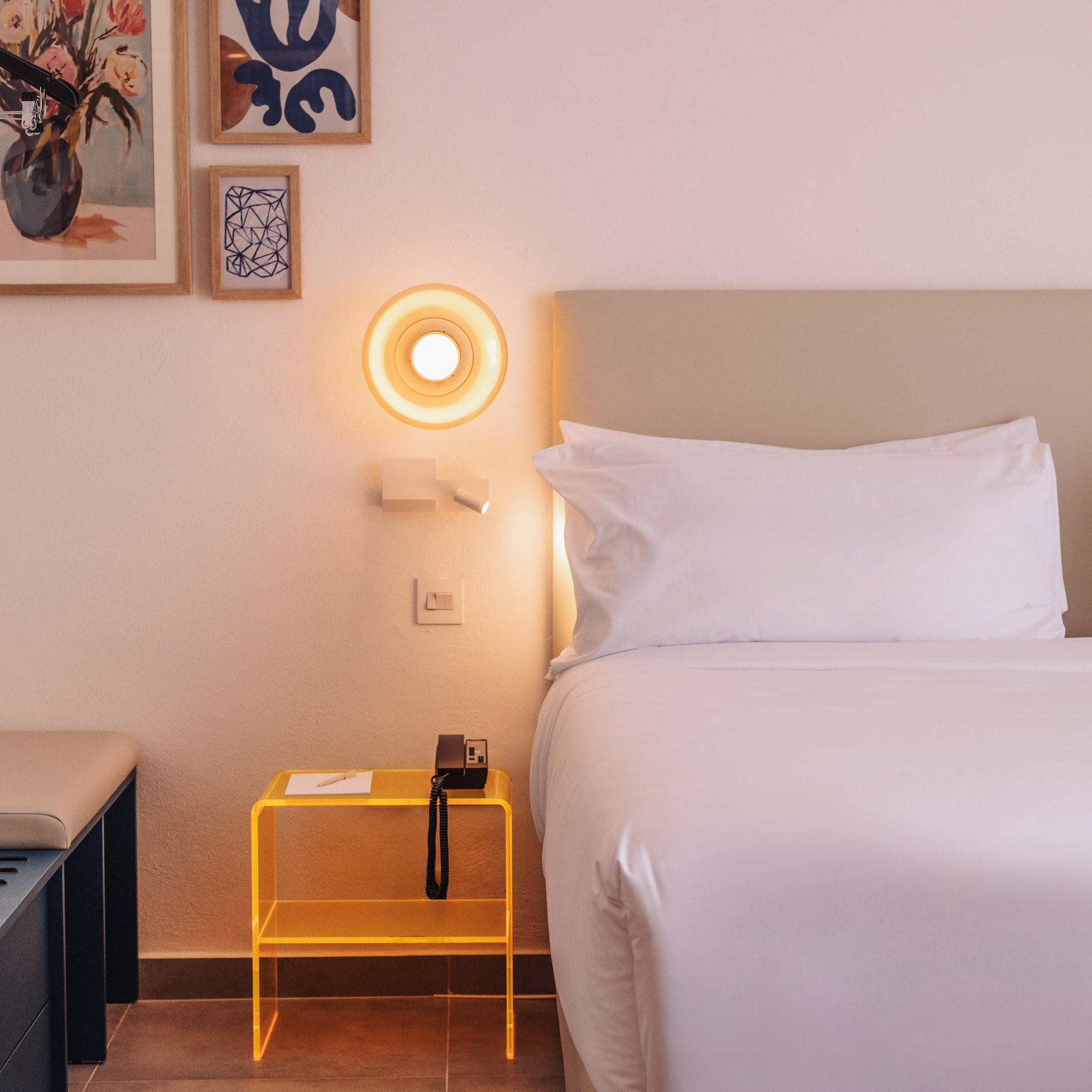 a bed with a yellow end table and a lamp