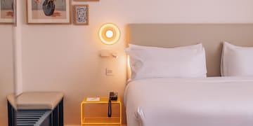 a bed with a yellow end table and a lamp