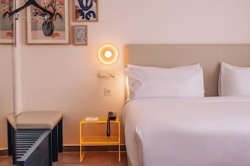 a bed with a yellow end table and a lamp