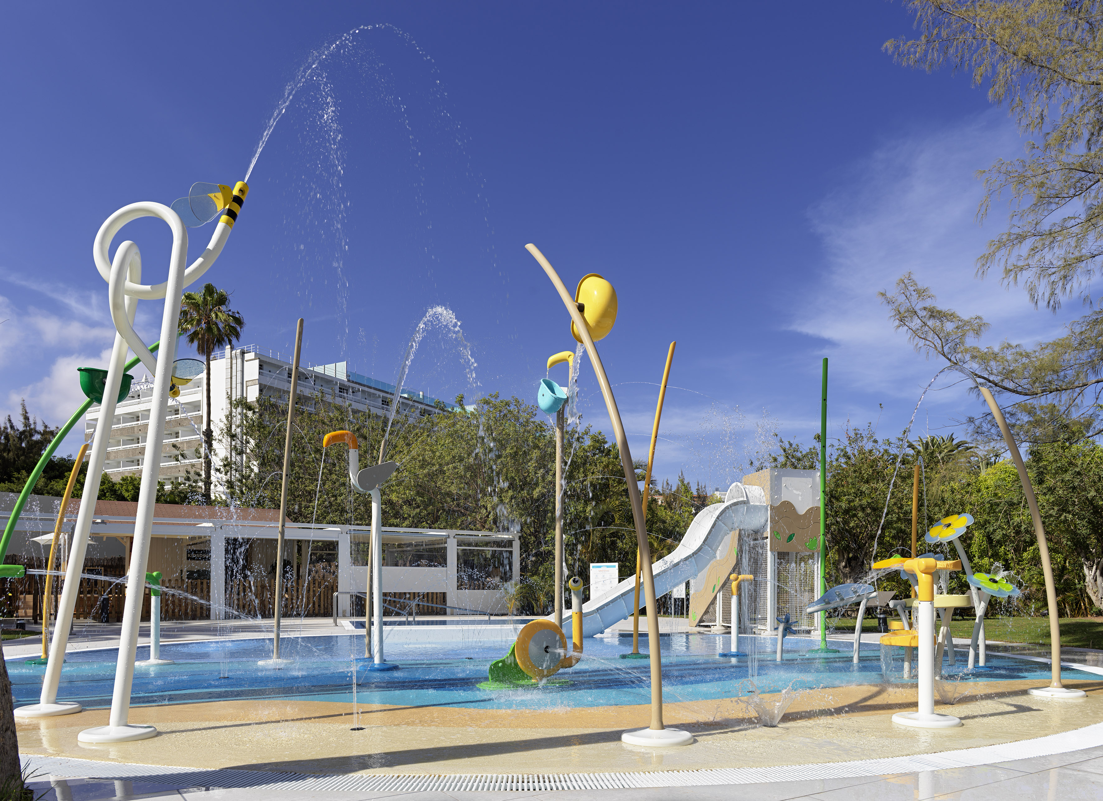 Colorful kids' water park splash pad with active water features and slide.