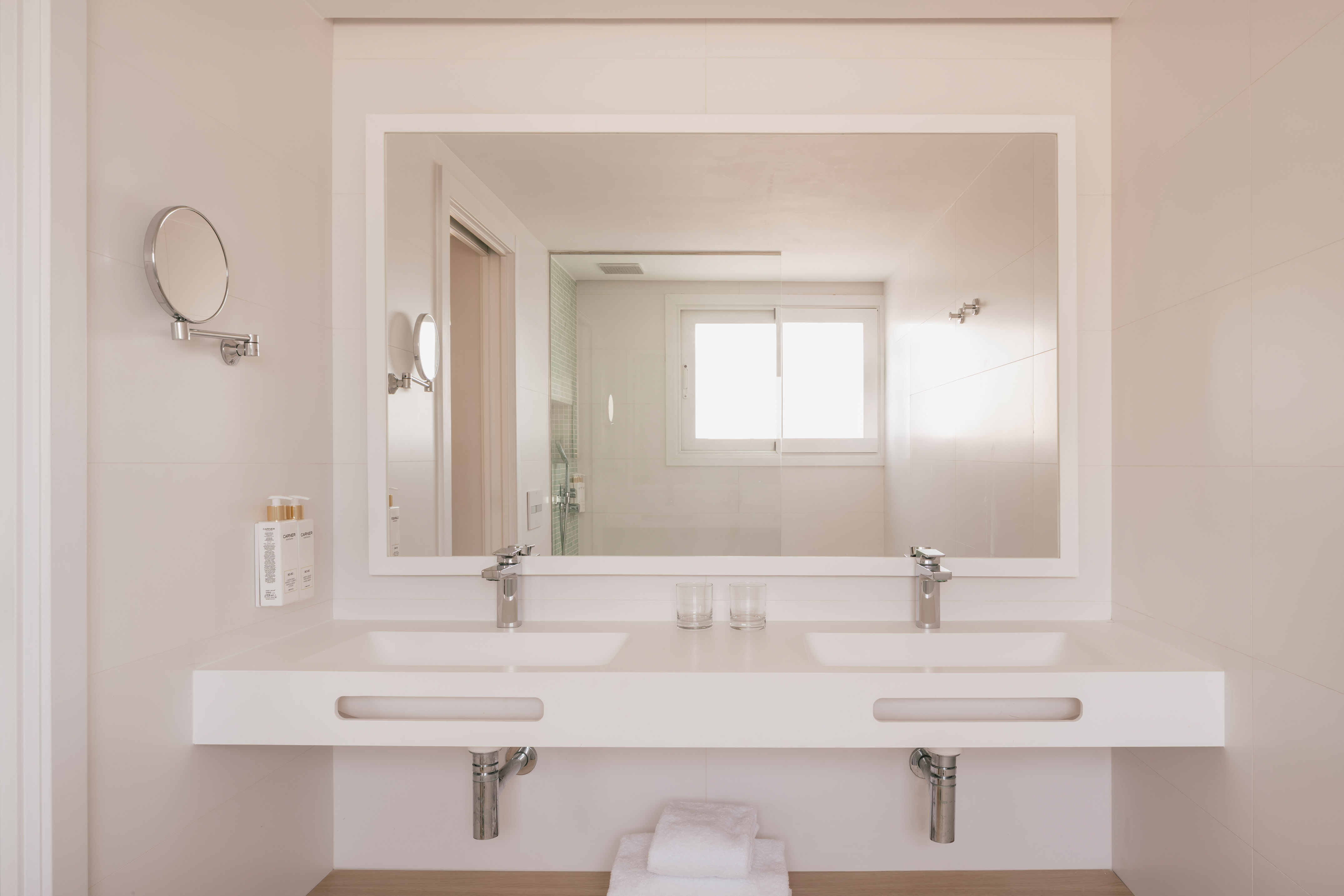 Baño moderno, doble lavabo blanco, espejo grande, diseño hotel.