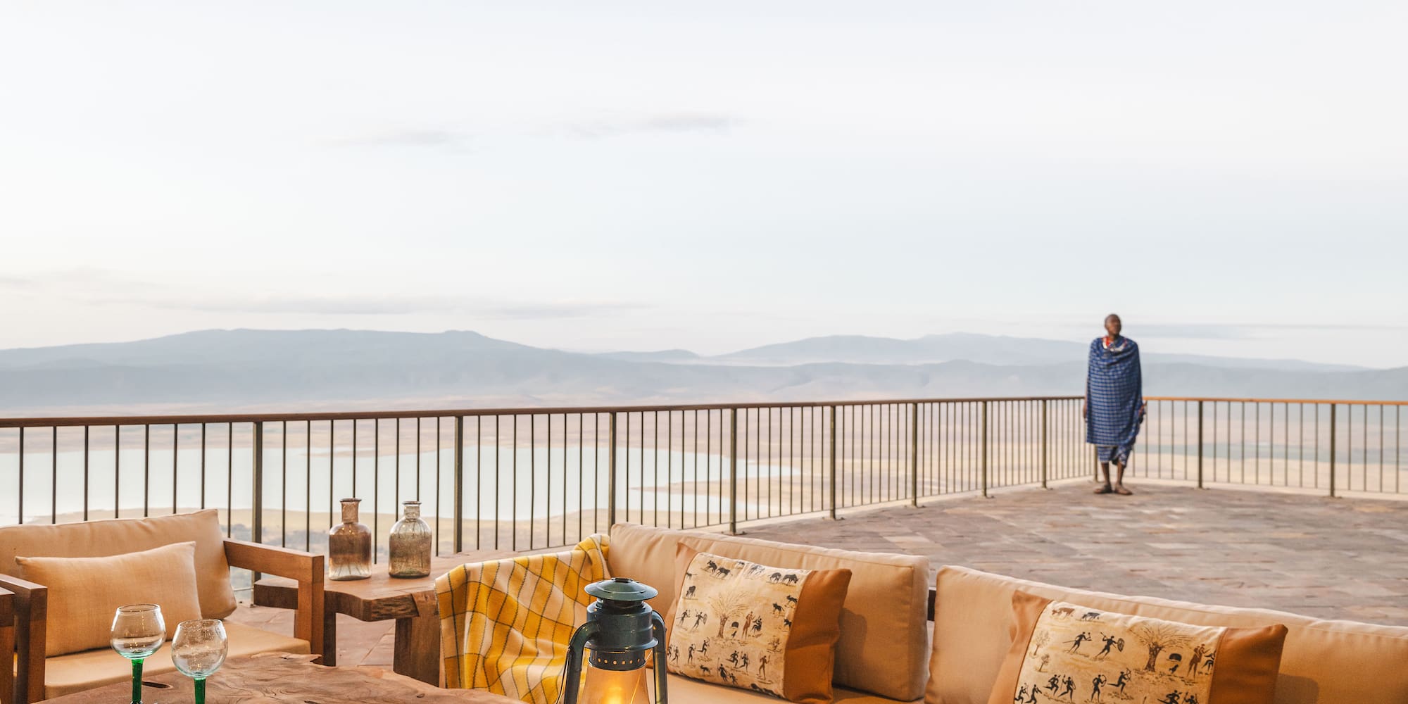 a table with pillows and a lamp on a deck with a person walking