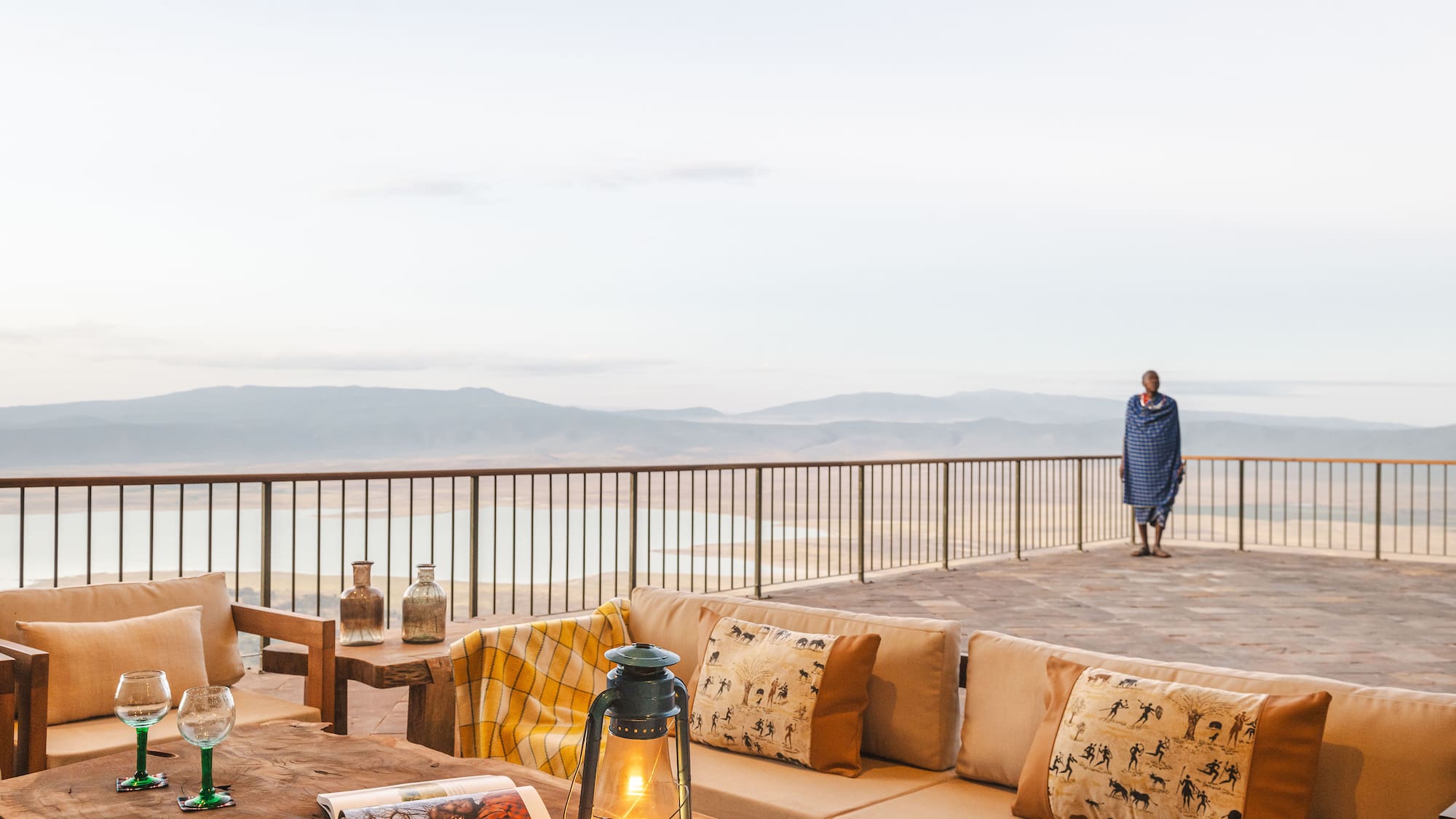 a table with pillows and a lamp on a deck with a person walking