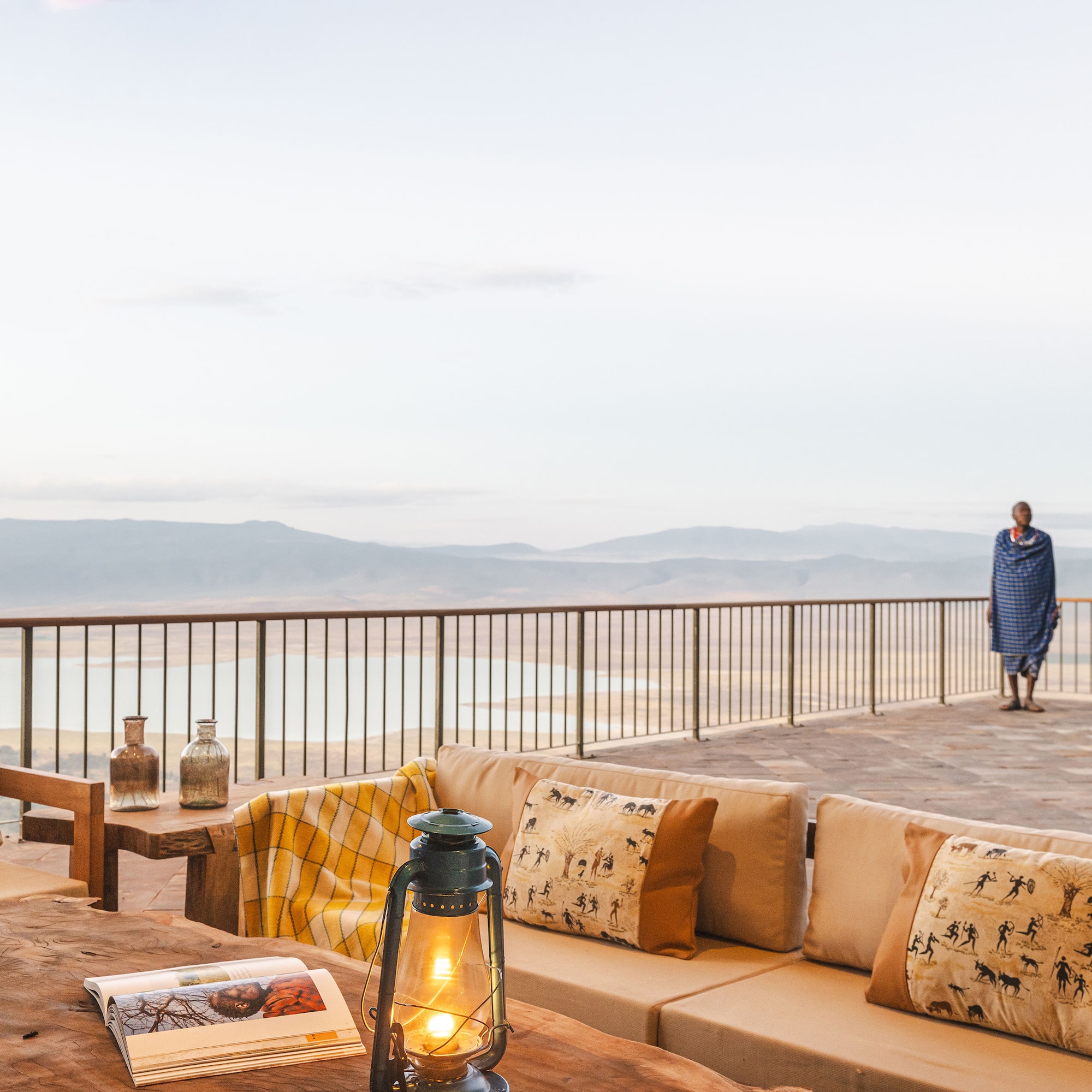 a table with pillows and a lamp on a deck with a person walking