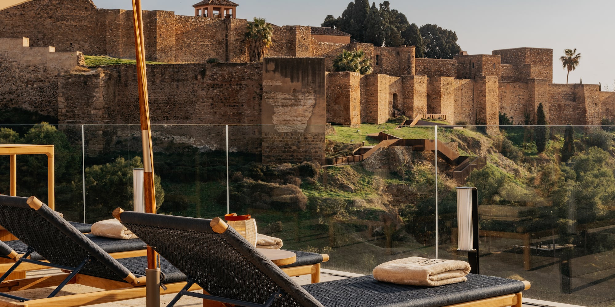 Lounge chairs on sunny terrace overlooking Alcazaba fortress, Malaga.