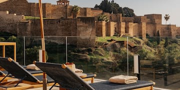 chairs on a patio with a large stone wall behind it