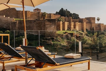 chairs on a patio with a large stone wall behind it