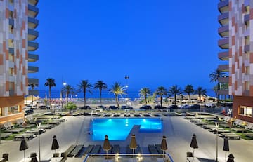 a pool with palm trees and a beach in the background